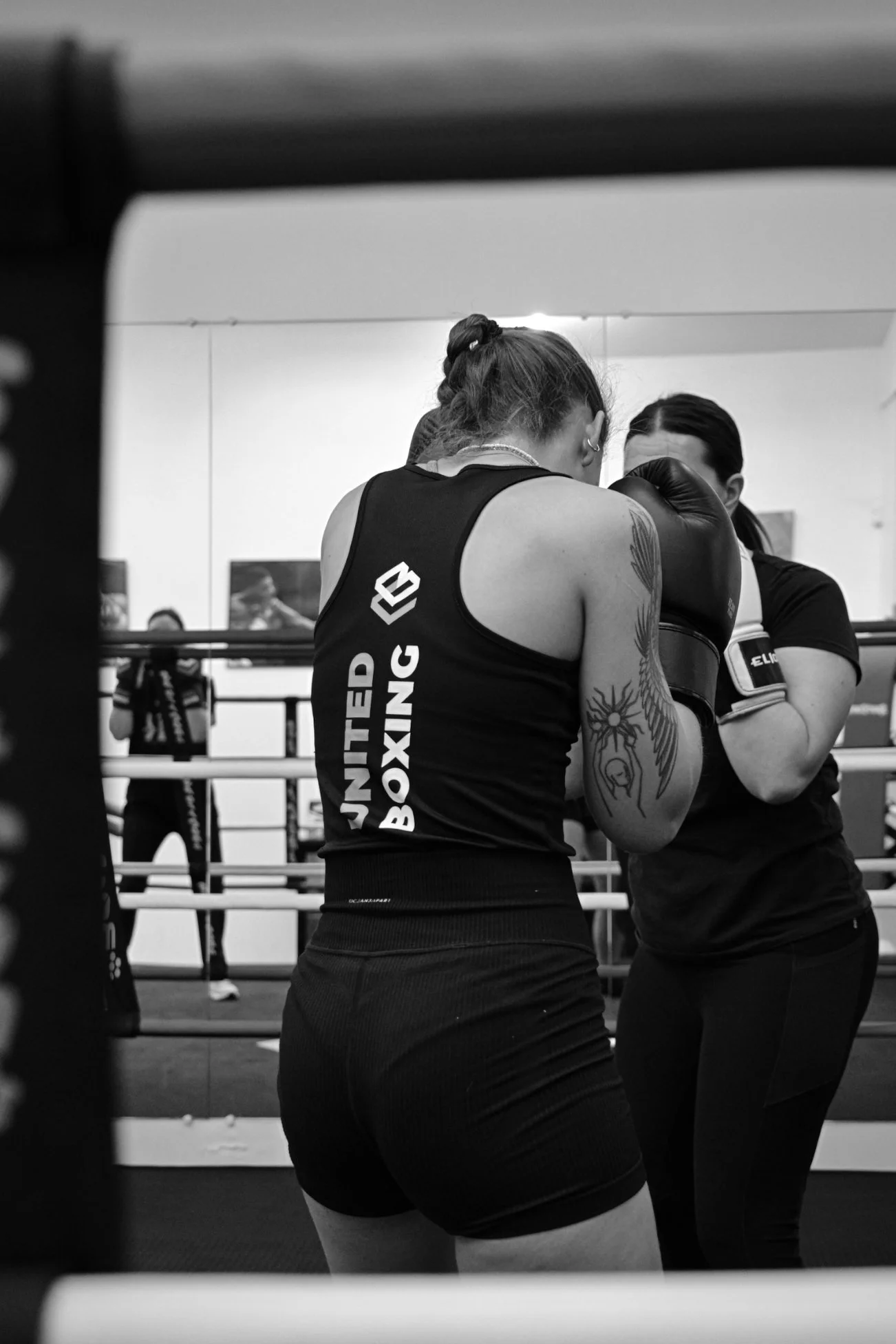 Deux femmes pratiquant la boxe anglaise en binôme sur le ring du club.
