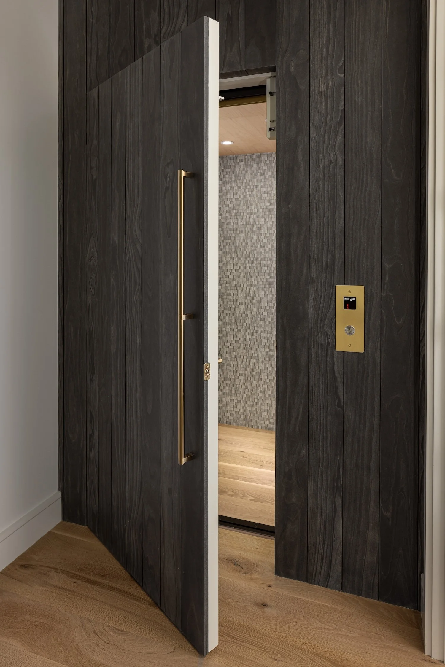 Custom wood feature wall with a concealed residential elevator and seamless millwork in a luxury Rhode Island custom home.