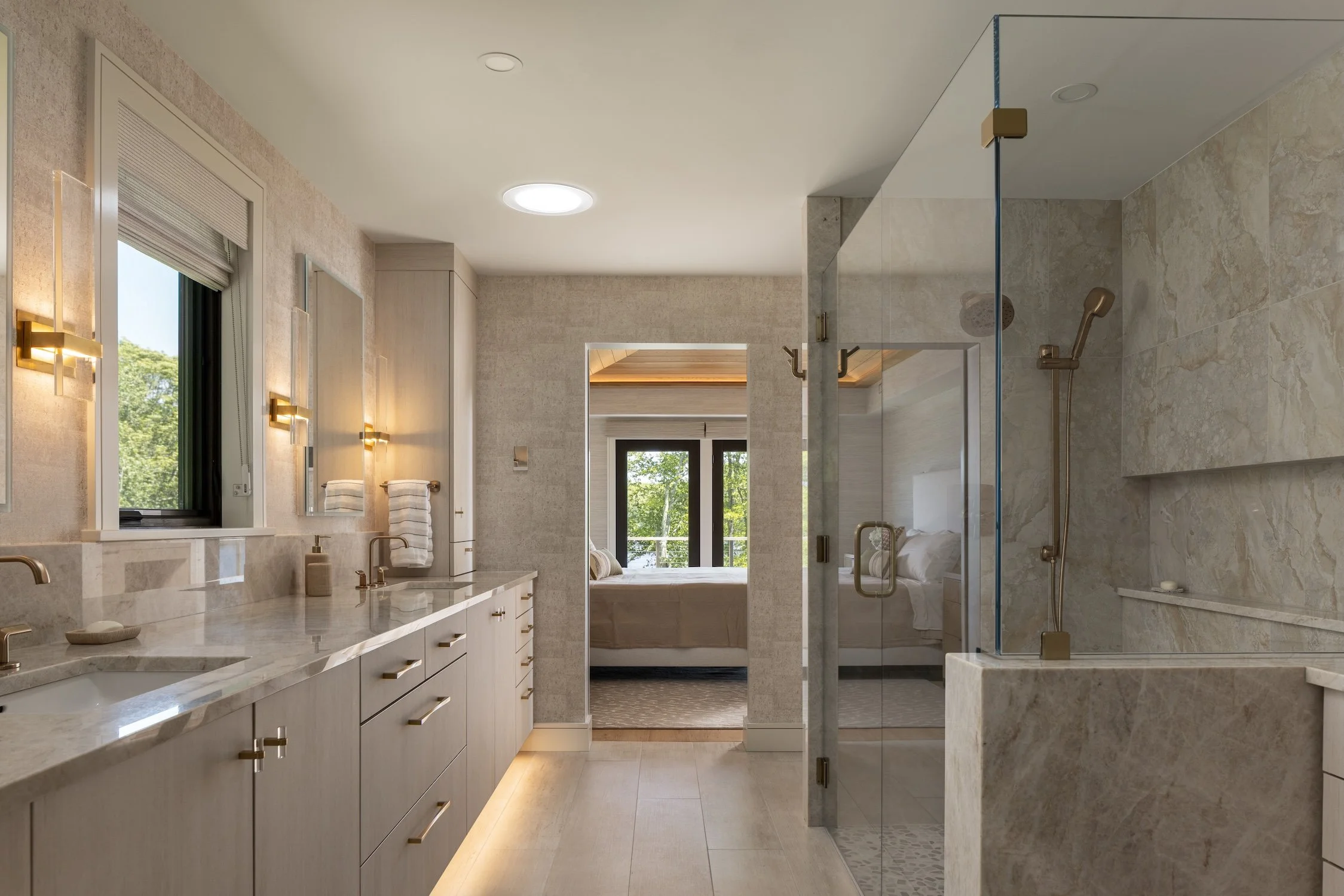 Luxury primary bathroom with a custom double vanity, marble surfaces, frameless glass walk-in shower, and spa-inspired finishes.