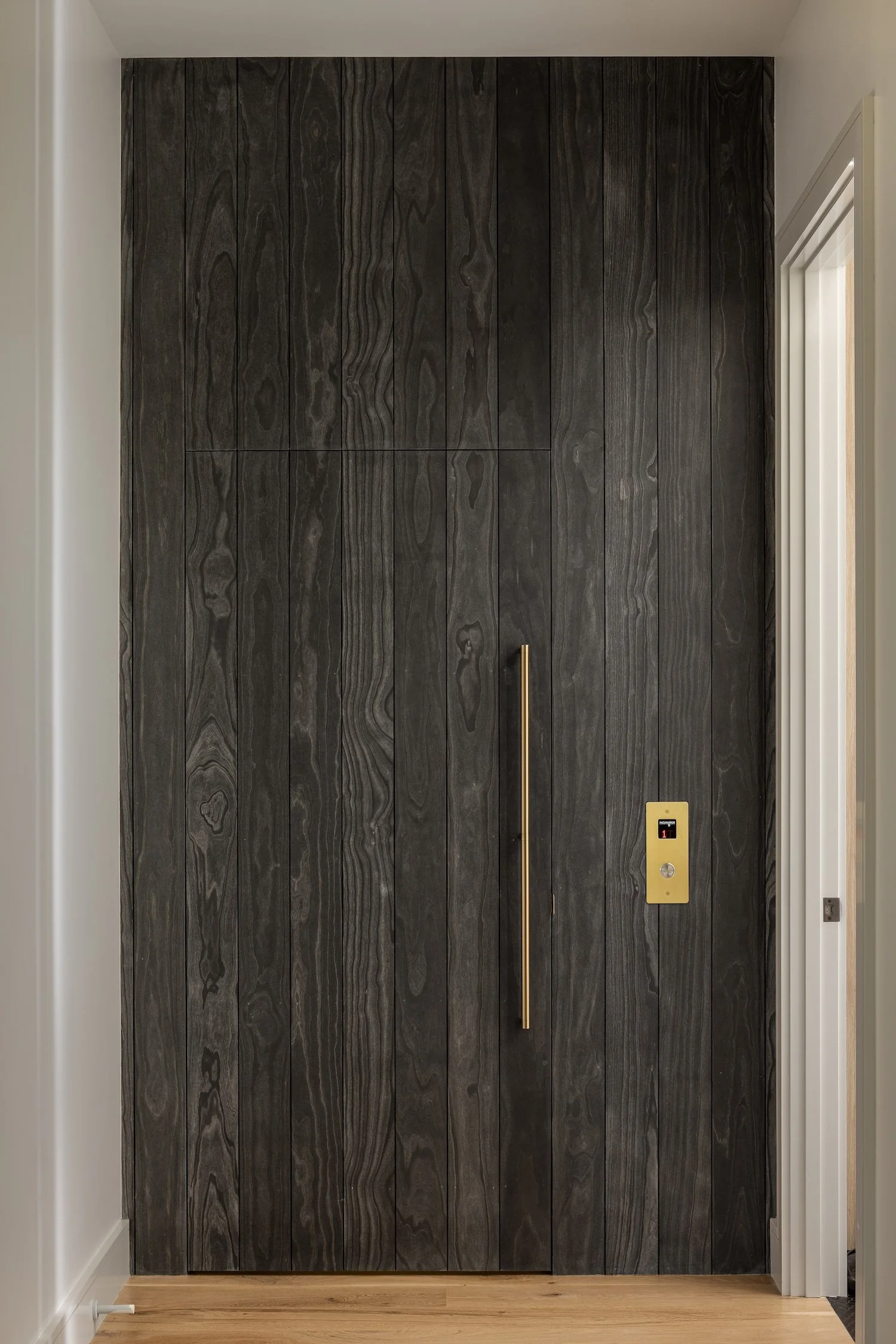 Custom wood feature wall with a concealed residential elevator and seamless millwork in a luxury Rhode Island custom home.