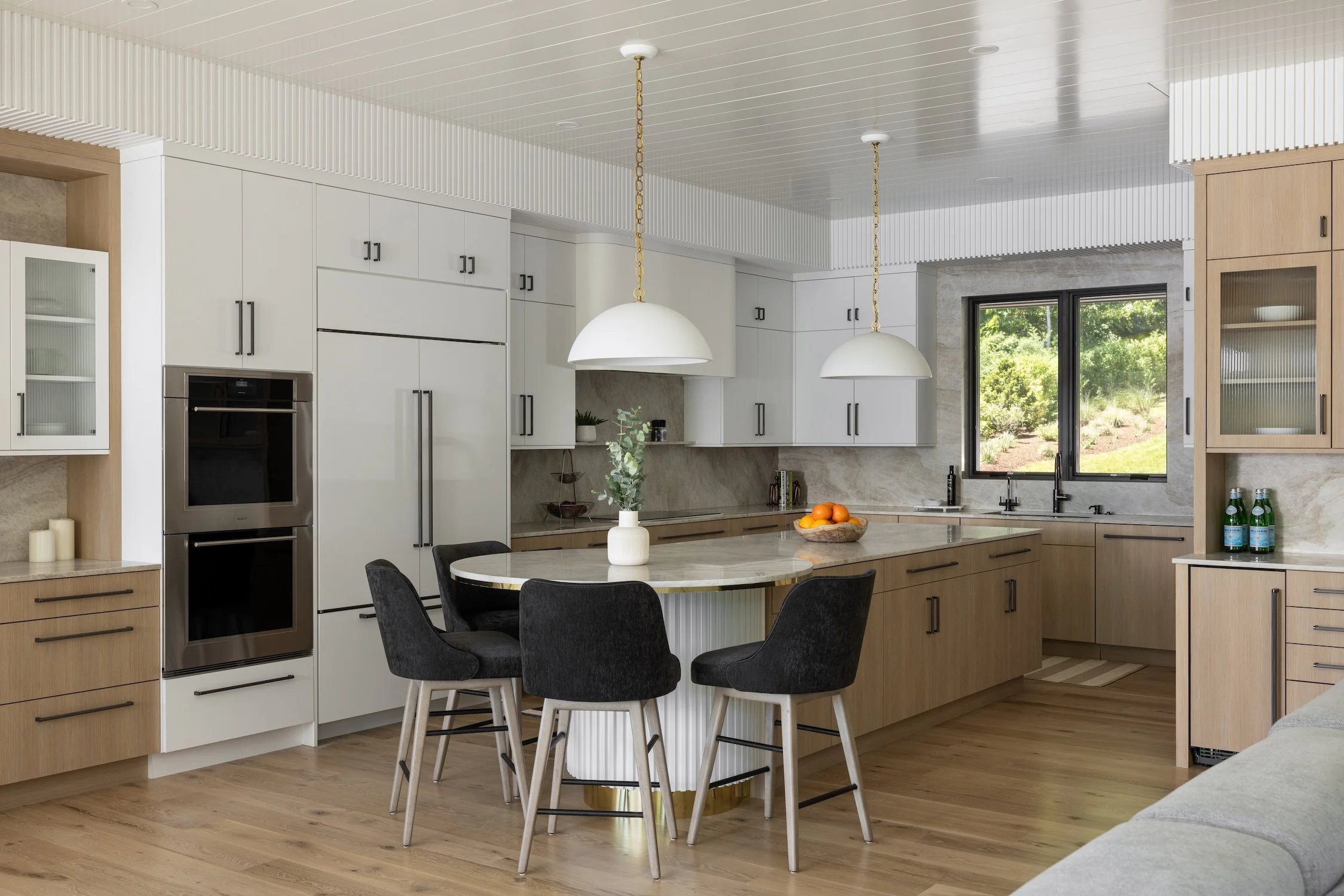 kitchen with island and white cabinets, wood toned built in cabinetry, white pendant lights, kitchen island