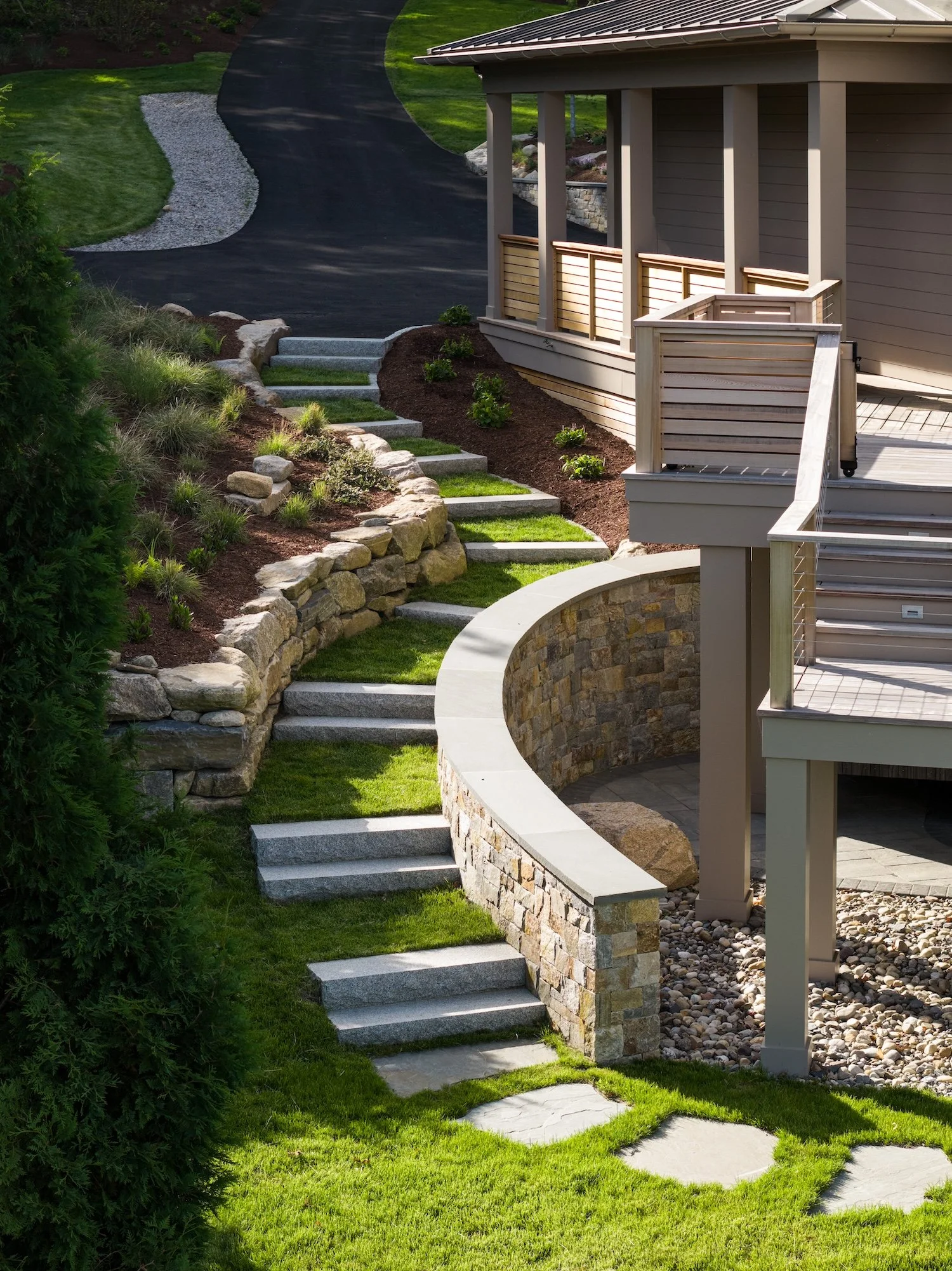 Custom stone retaining walls, granite steps, and landscaped outdoor living spaces at a luxury Rhode Island waterfront home.