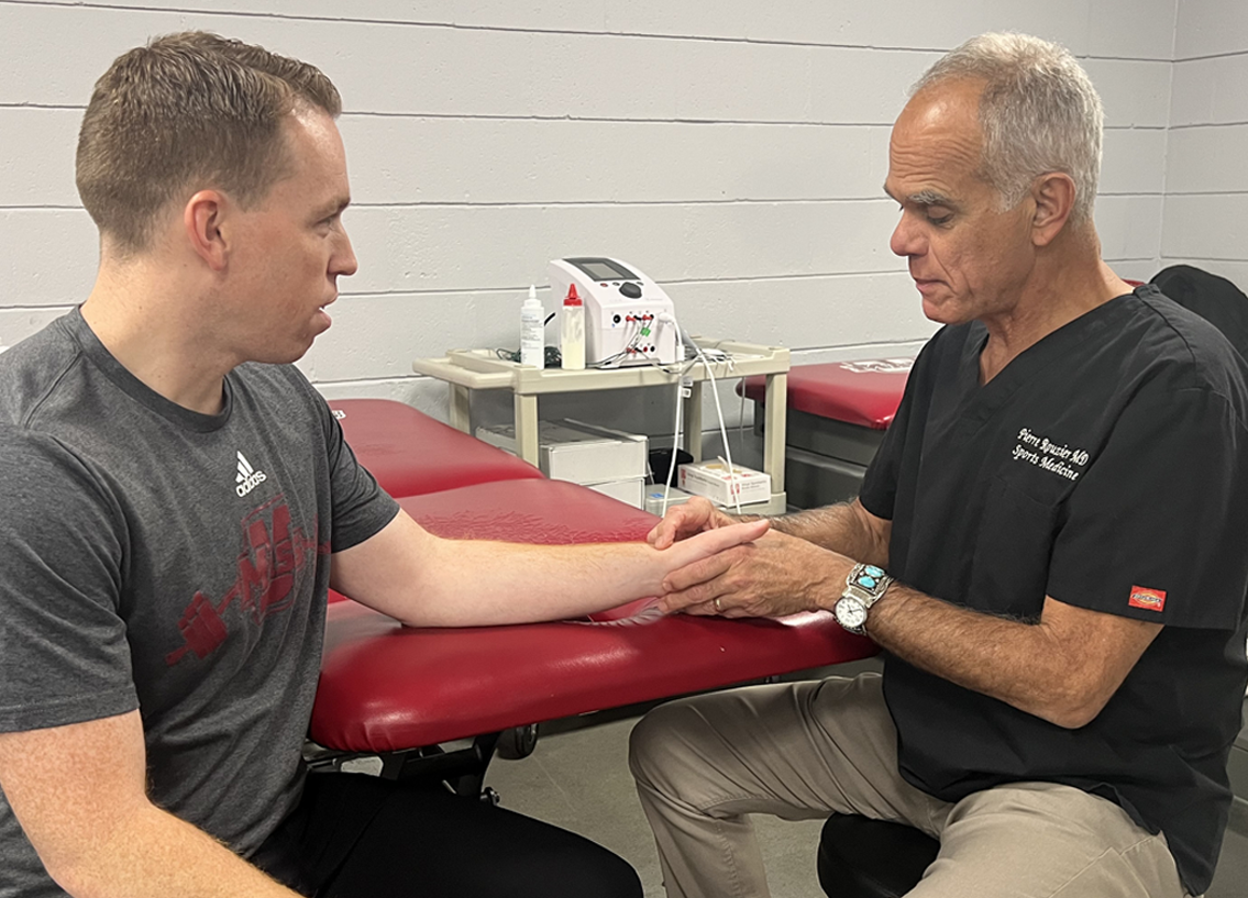 A medical professional examines a patient's arm in a clinic setting.