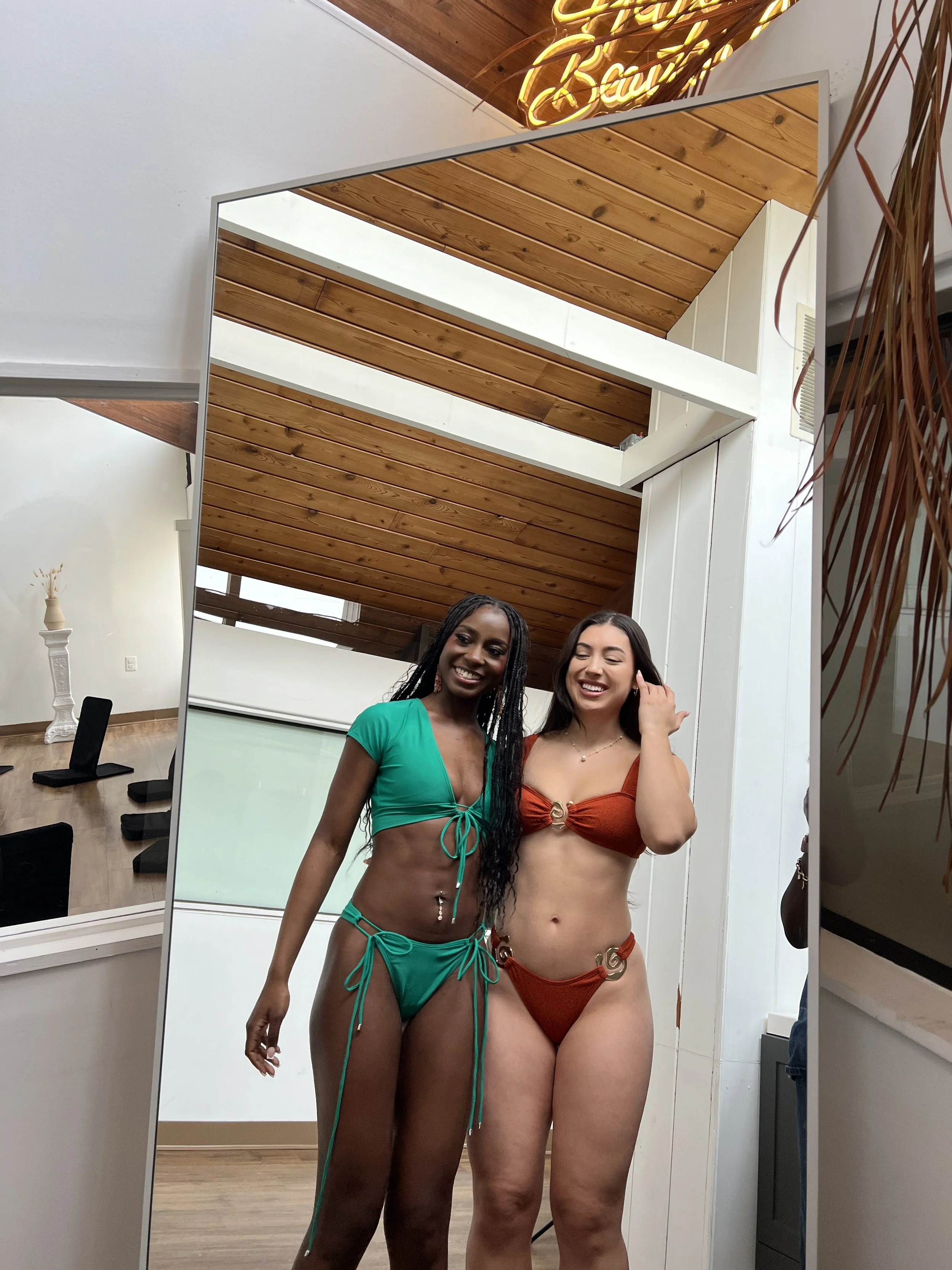 Two models wearing green and rust bikinis for size comparison. Meena Swims size guide shows how different body types wear the same styles, helping customers choose the best bikini size.