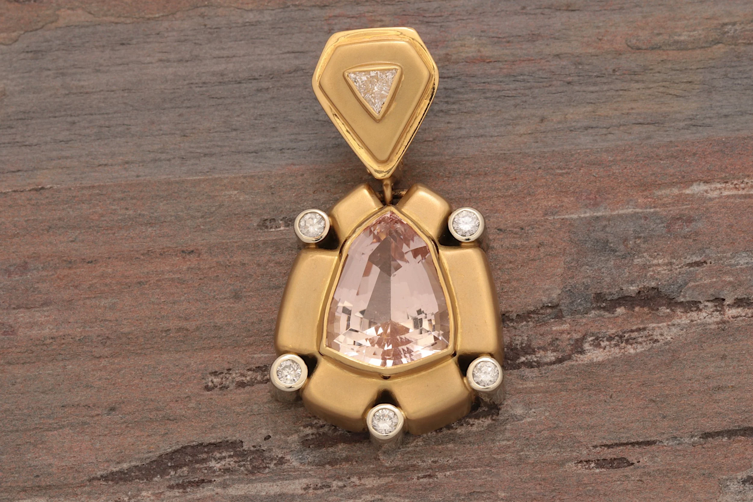 Morganite & Diamond Enhancer Pendant
Designed for versatility, this 18K gold pendant features a custom-cut morganite accented by nearly half a carat of Lazard Kaplan-cut diamonds. A smaller trillion-cut diamond adorns the hinged bail, which allows th