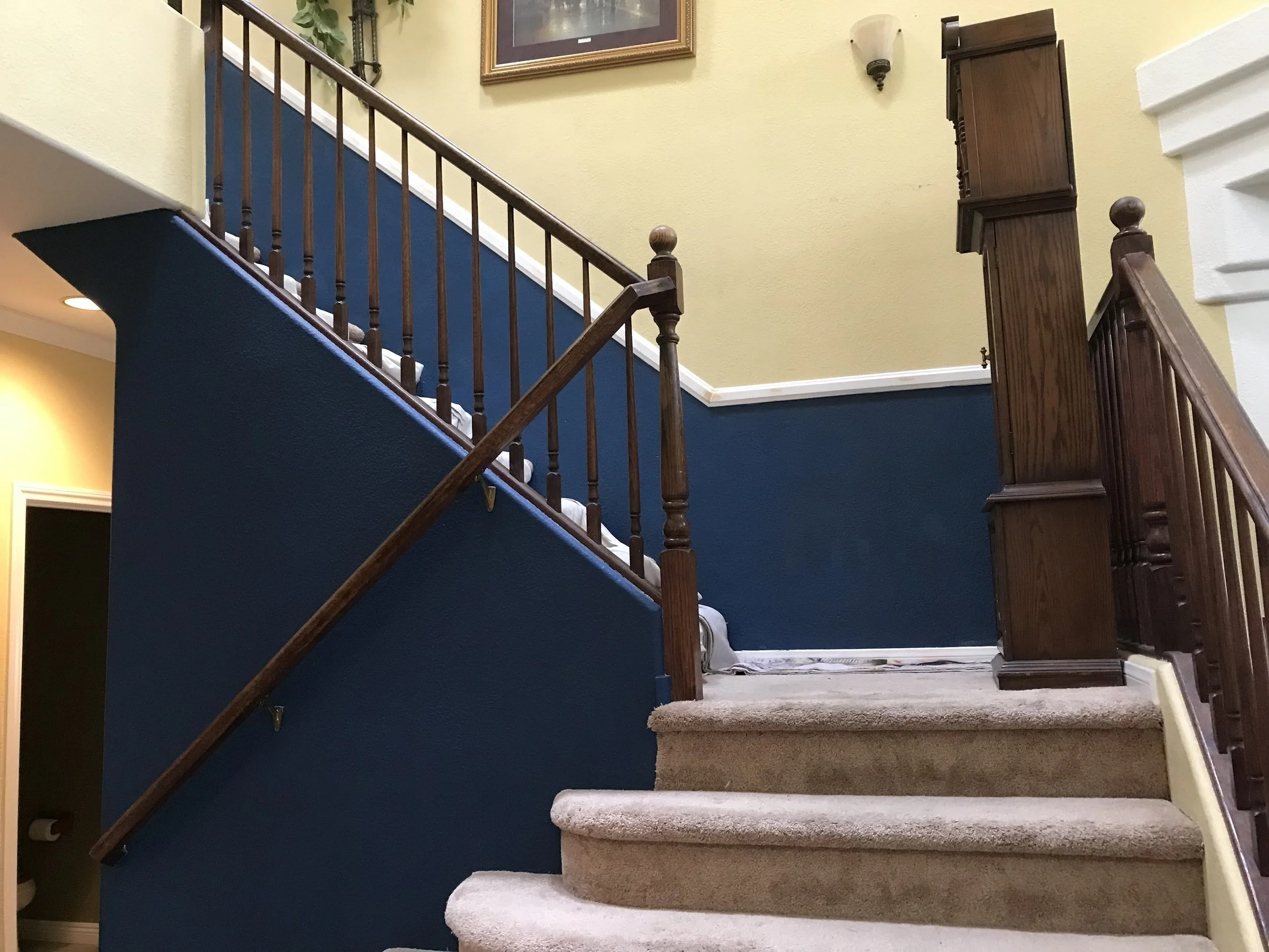 Indoor staircase with dark wooden railing and blue and yellow walls