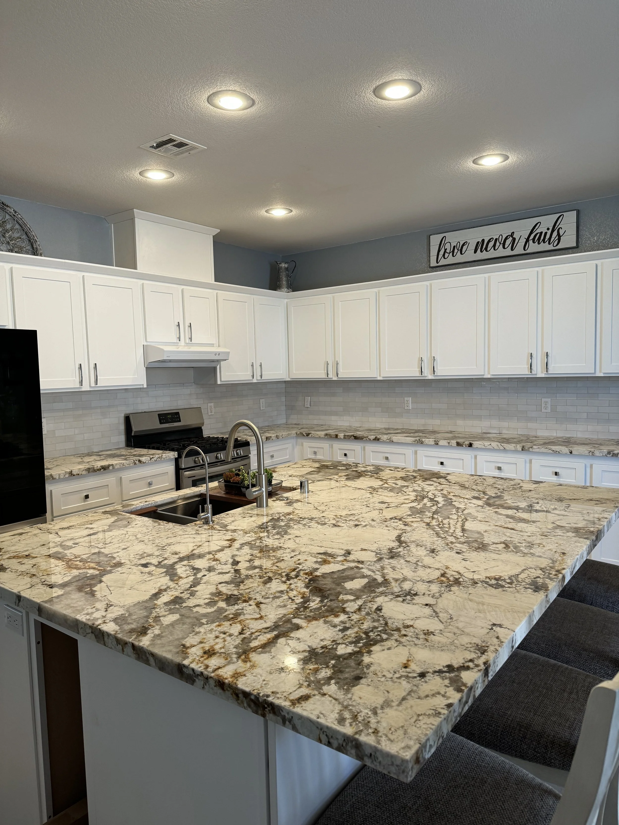 Modern kitchen with white cabinets, granite countertops, stainless steel appliances, and recessed lighting.