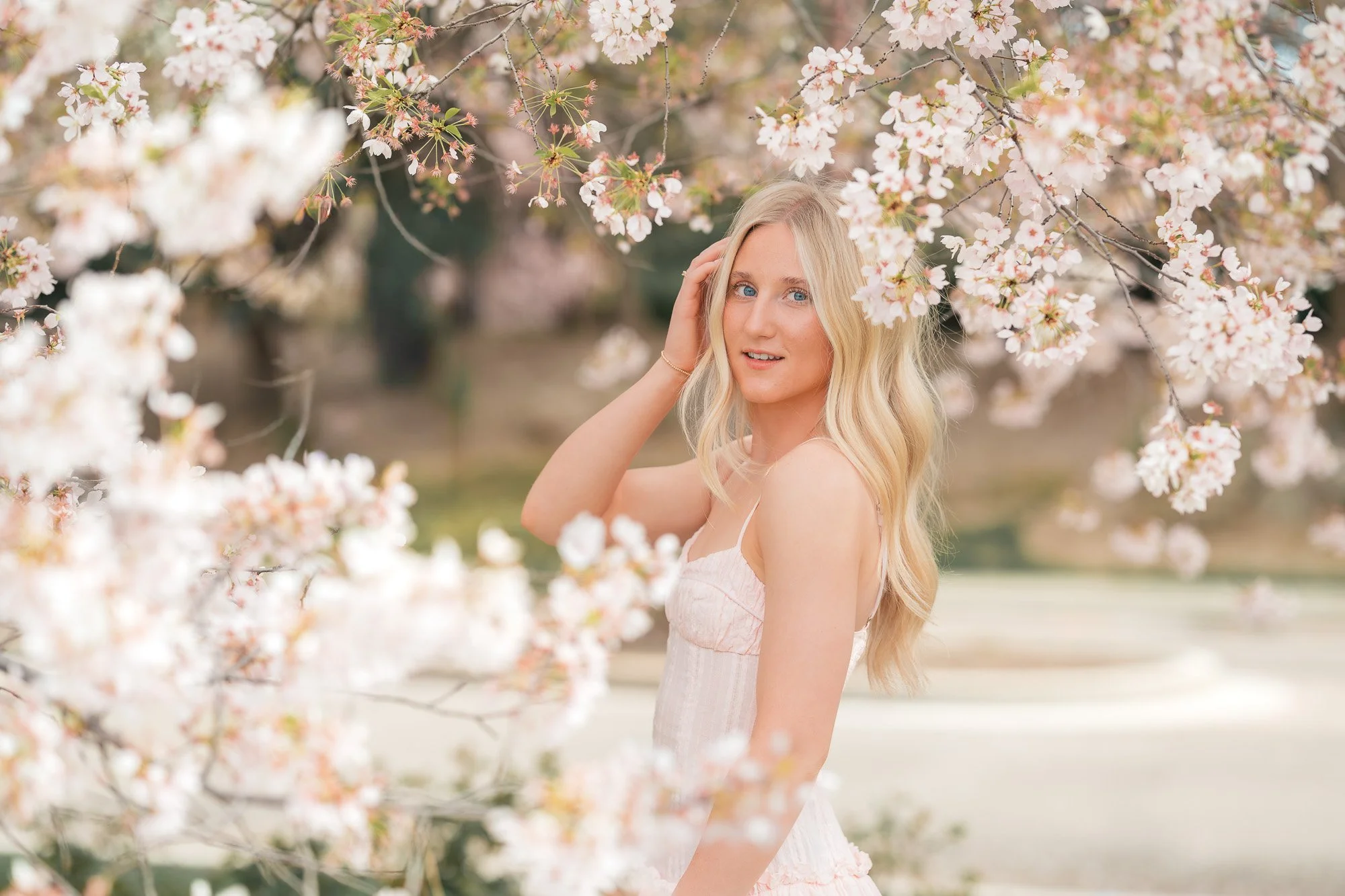 Eagle high school student wearing a pink dress, taking pictures in the cherry blossoms.