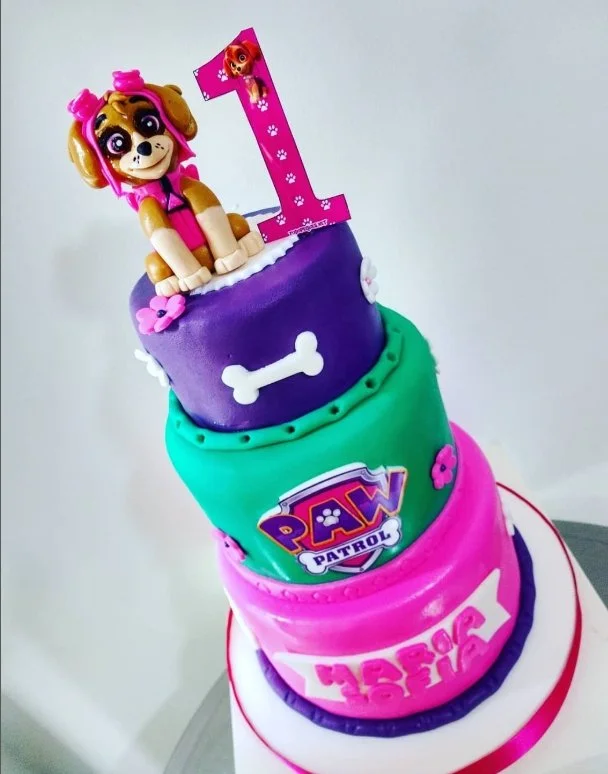 Pastel de cumpleaños de Paw Patrol con figura de una perrita y un número uno en la parte superior