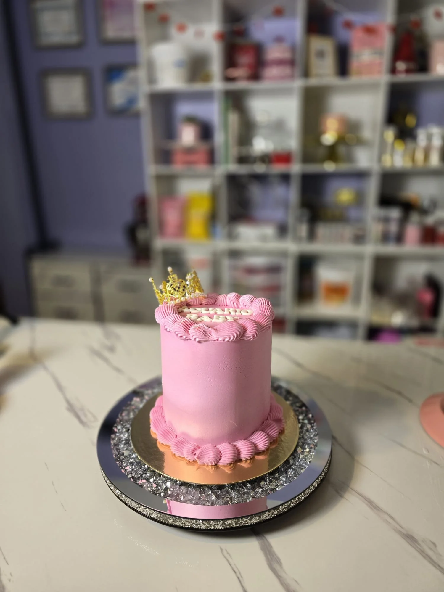 Pastel de cumpleaños rosa con corona dorada y decoración de crema. 