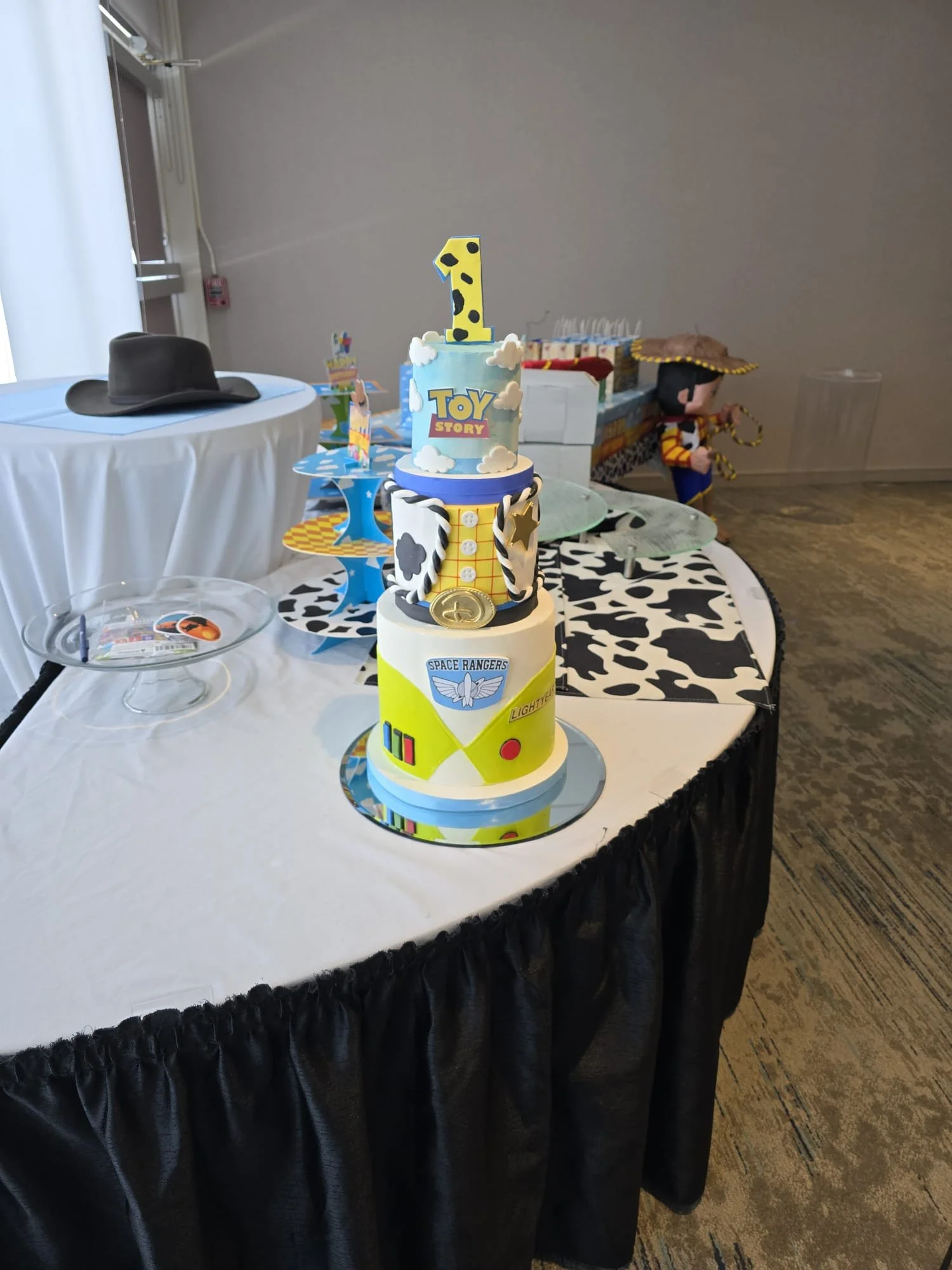 Pastel de cumpleaños con decoraciones temáticas de Toy Story y personajes de dibujos animados, en un entorno de fiesta infantil.