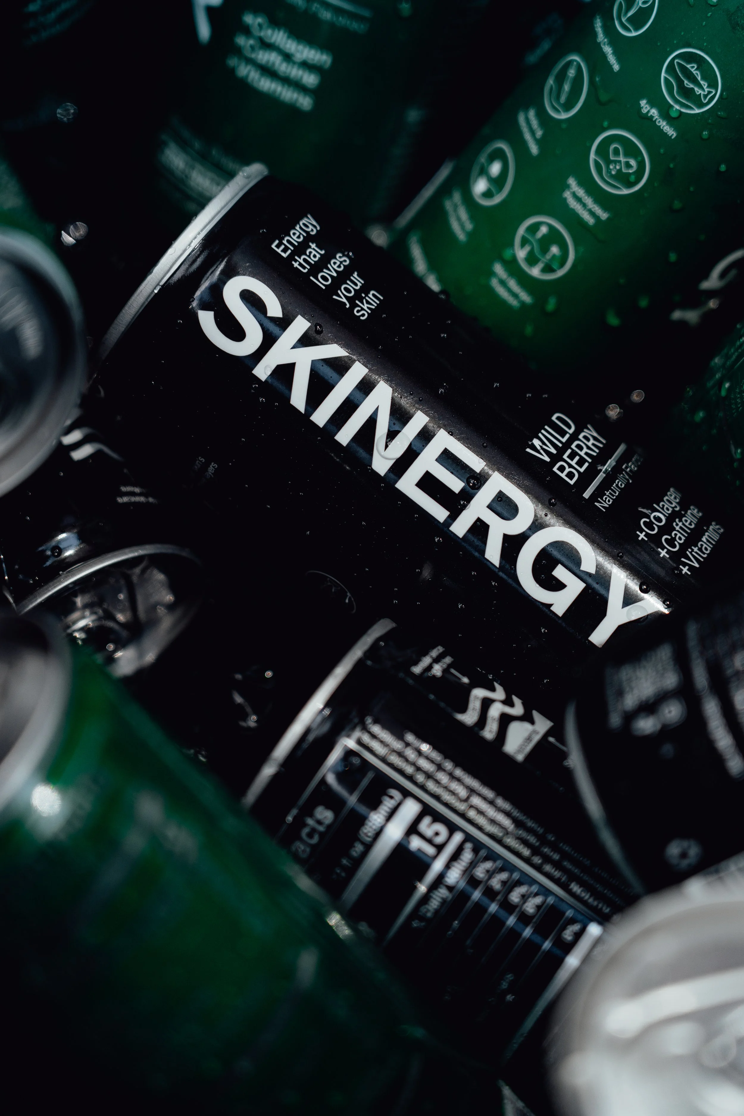 Close-up of canned beverages, with one can labeled 'SKINNER', indicating it is a berry-flavored drink, among other cans in the background.