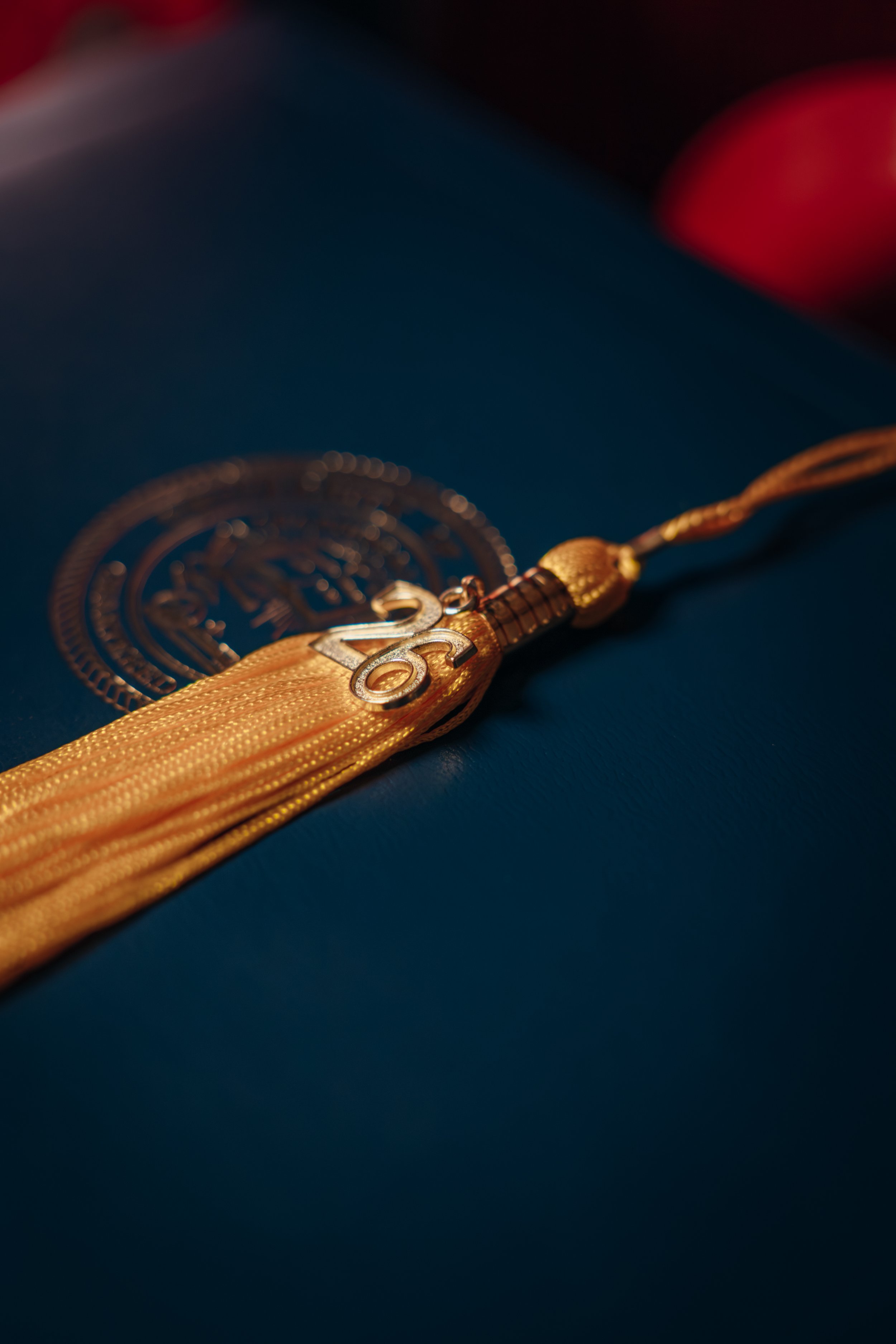 Close-up of a gold medal with a ribbon, featuring the number 2023 and a design, placed on a dark background.