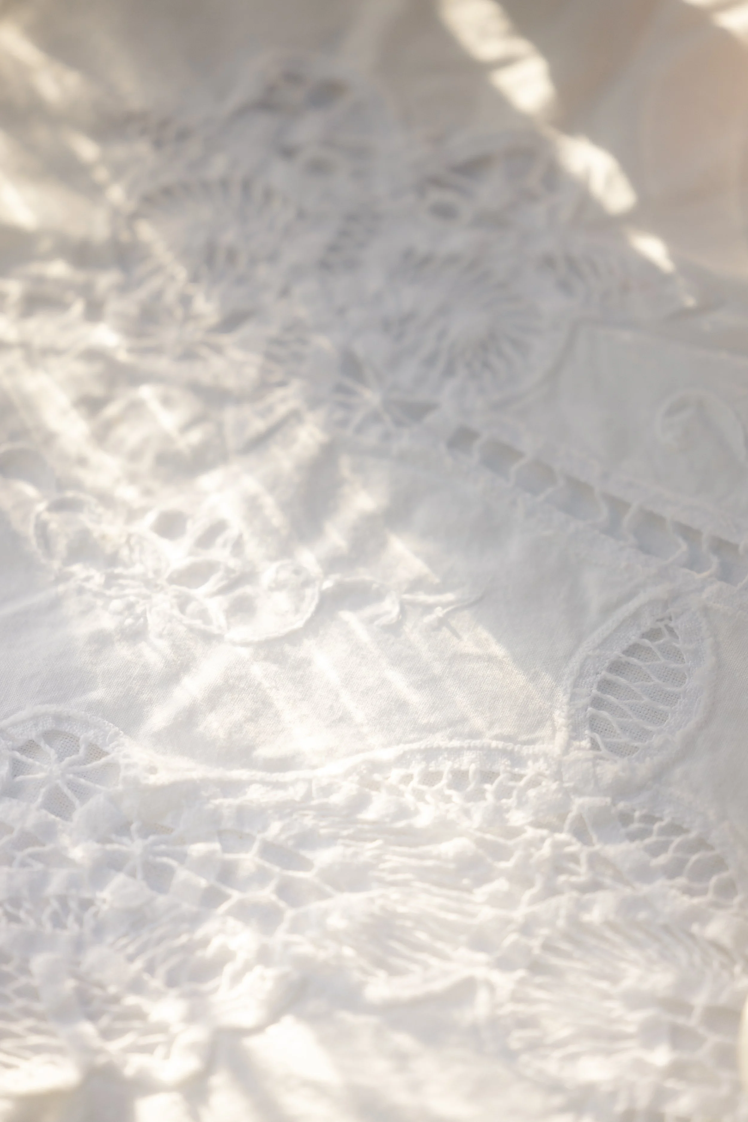 Close-up of delicate white lace fabric with floral patterns and soft folds