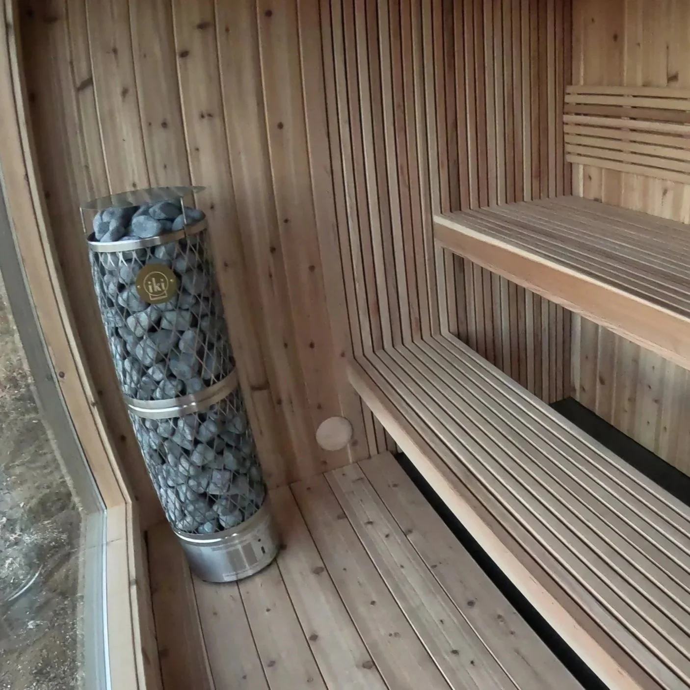 Traditional custom sauna interior with wood benches and classic sauna heater stones.