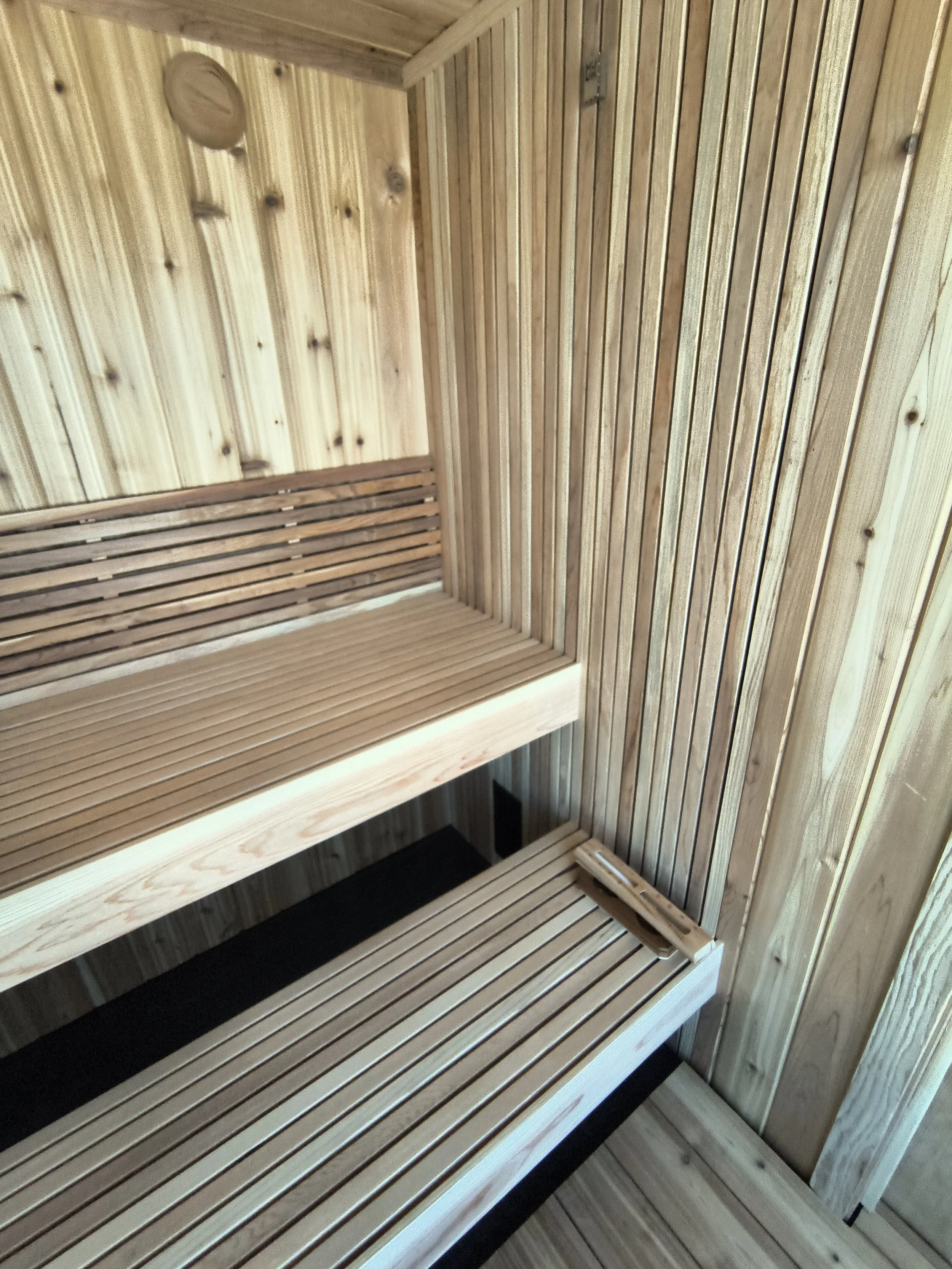 Interior of a traditional sauna with wooden benches and wood-paneled walls.