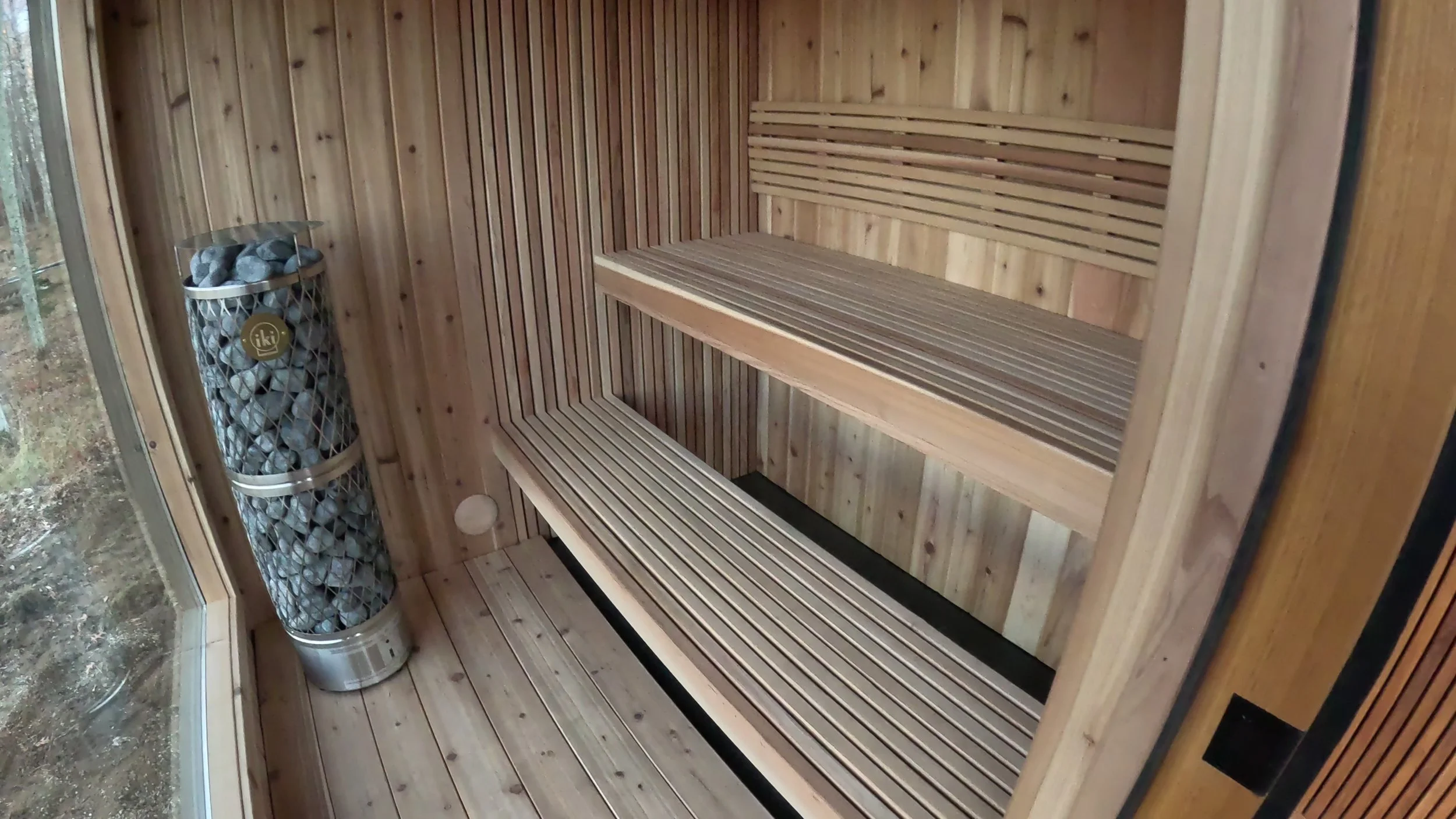 Traditional custom sauna interior with wood benches and classic sauna heater stones.