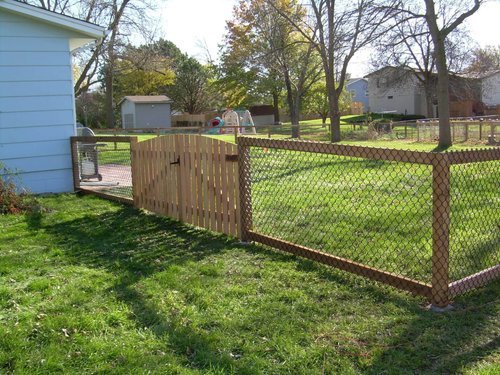 Backyard with wooden gate, chain-link fence, and lawn