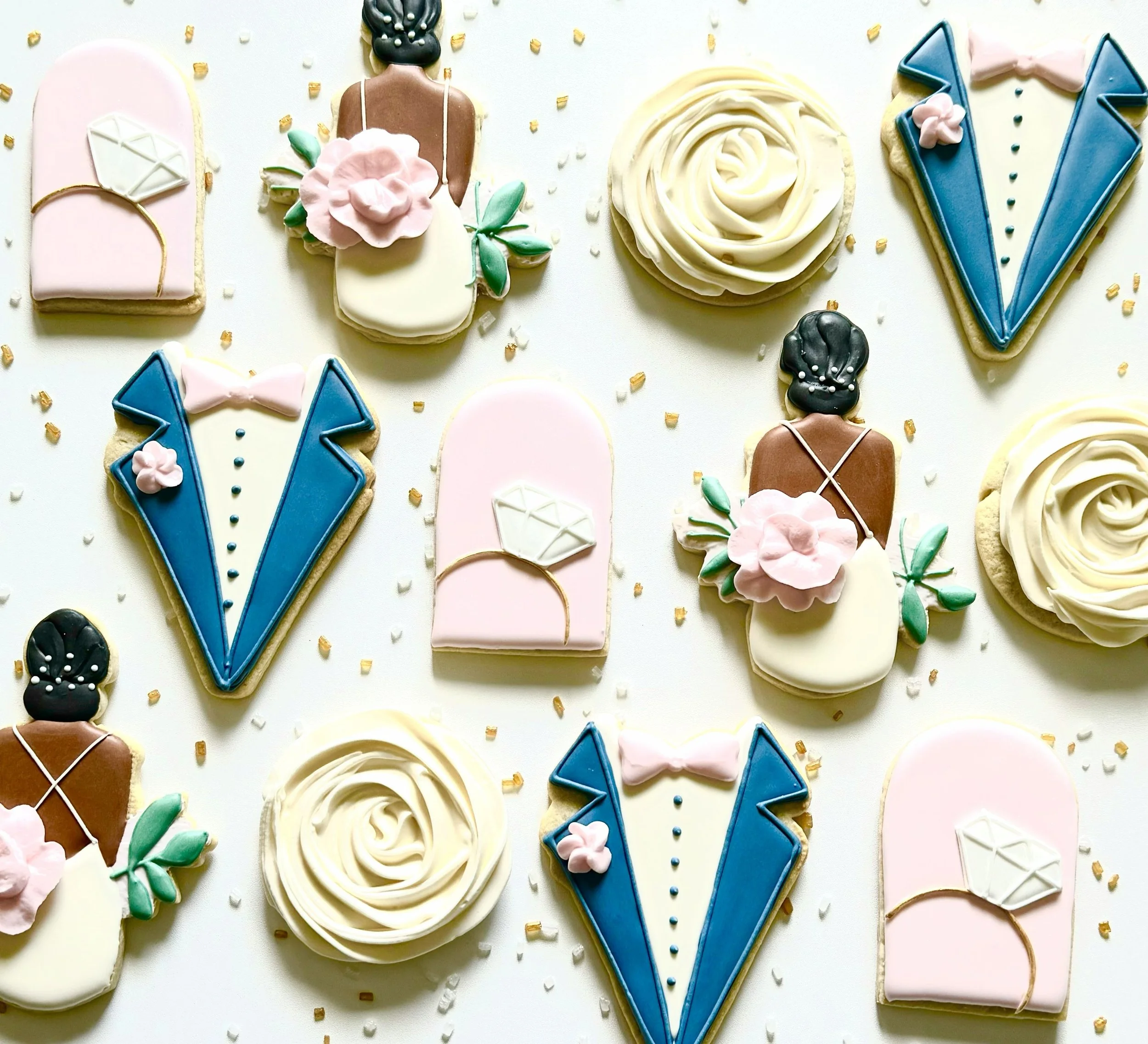 Decorated cookies with wedding-themed designs, including tuxedo and bride dress, floral accents, and roses.