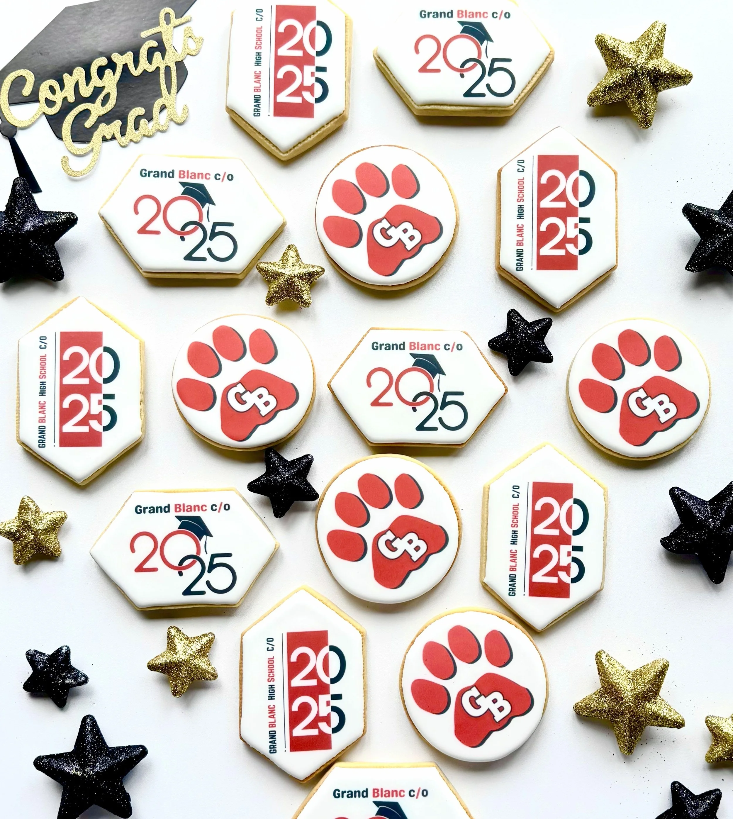 Decorative cookies celebrating graduation and high school graduation year 2025, featuring a paw print with diploma, graduation caps, gold and black star-shaped decorations, and a "Congratulations" sign.