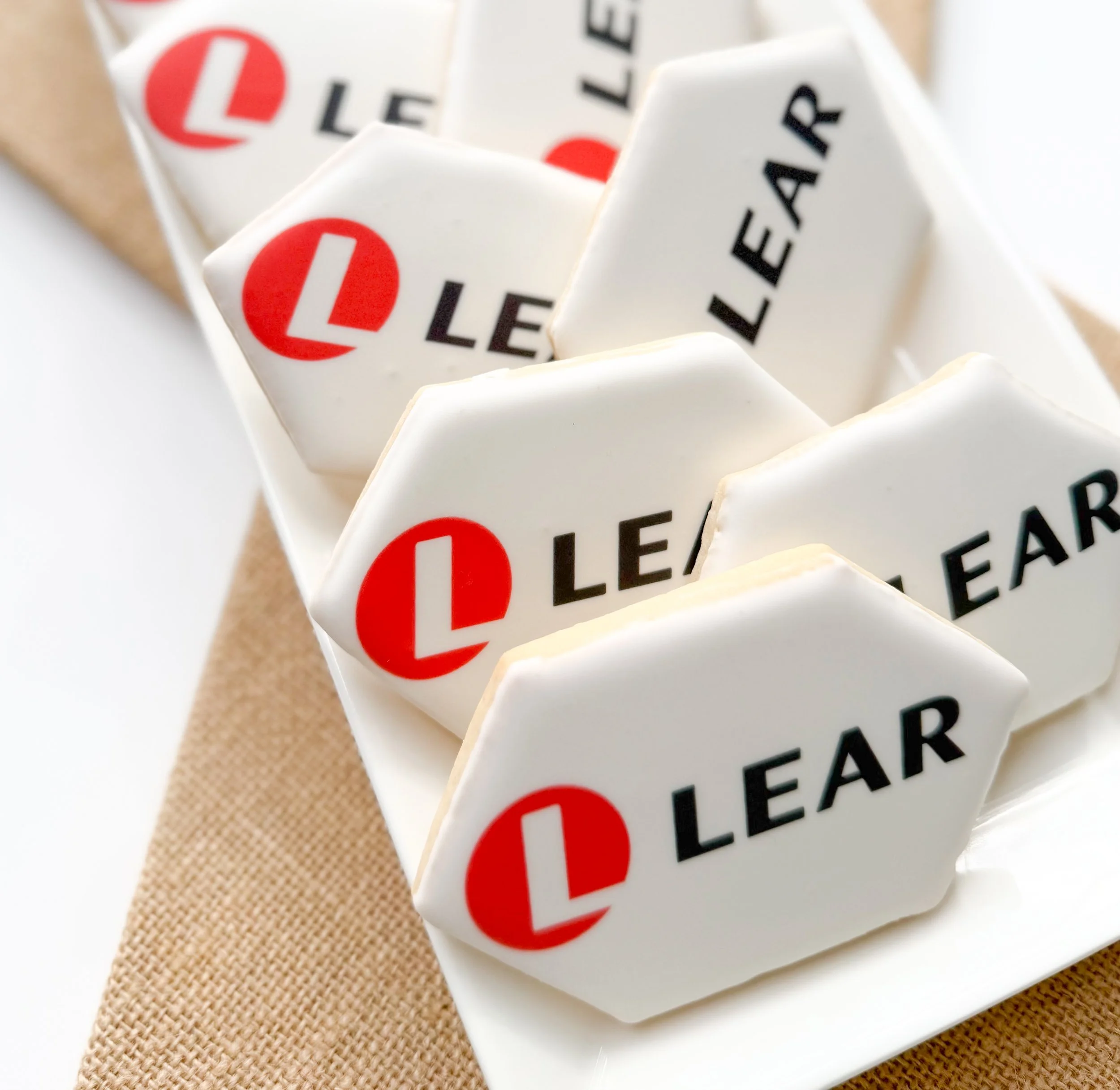 Close-up of multiple white tiles with the letter 'L' in red and black letters spelling out the word 'LEAR' The tiles are arranged on a beige, textured surface.