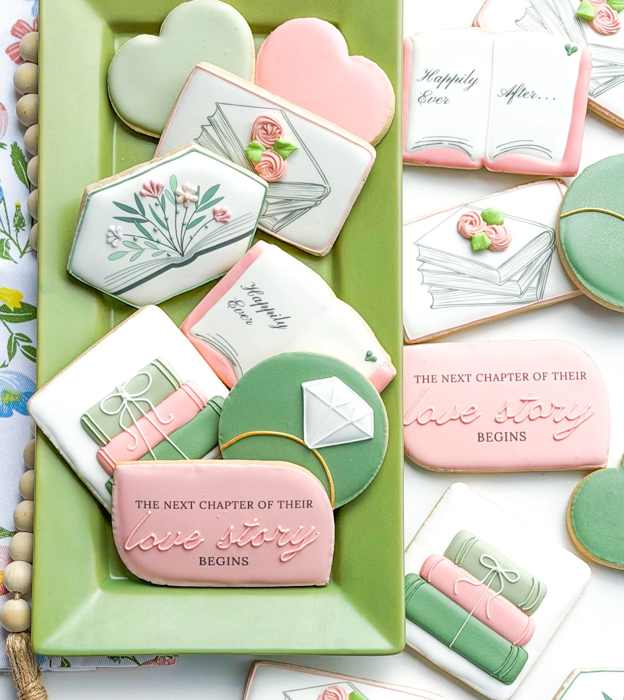 Decorative cookies with book and love themes, featuring pastel colors, flowers, gifts, hearts, and messages about love and life chapters.