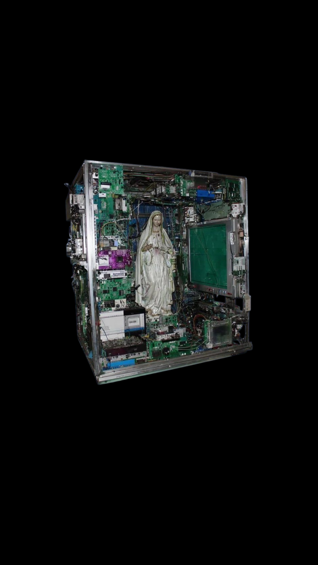 A statue of the Virgin Mary inside a transparent computer case filled with electronic components and circuit boards, with a small screen on the right.