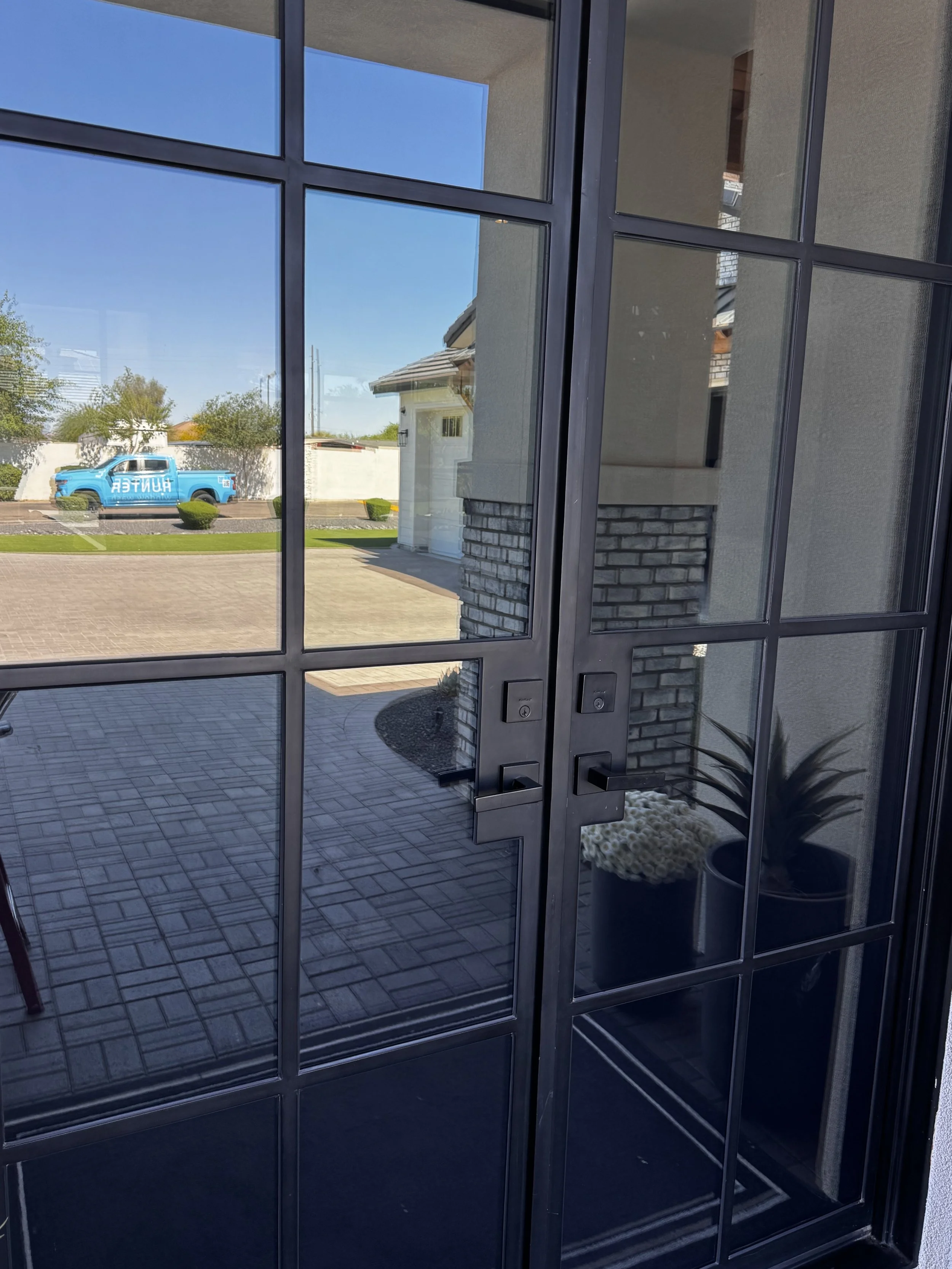 large glass door with black panes all clean showing reflection of Hunter Window Wash truck