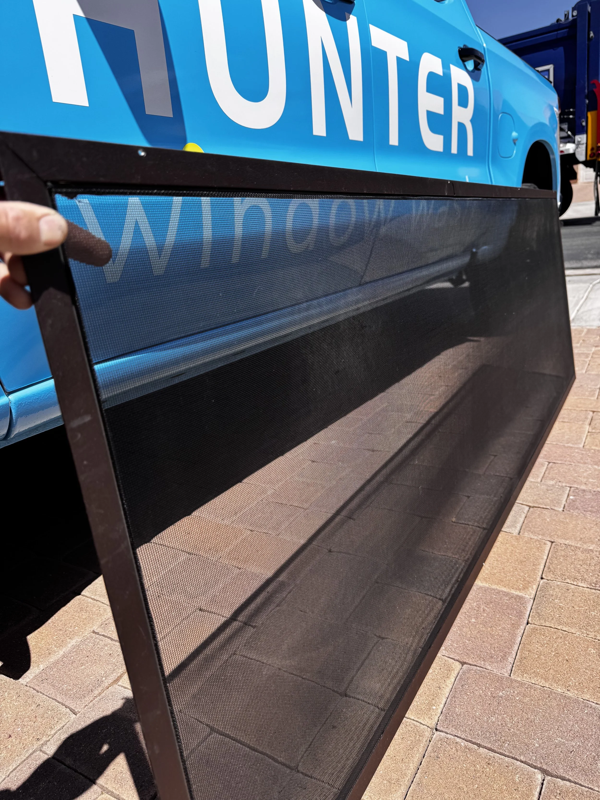 photo of a clean window screen in front of the blue Hunter Window Wash truck