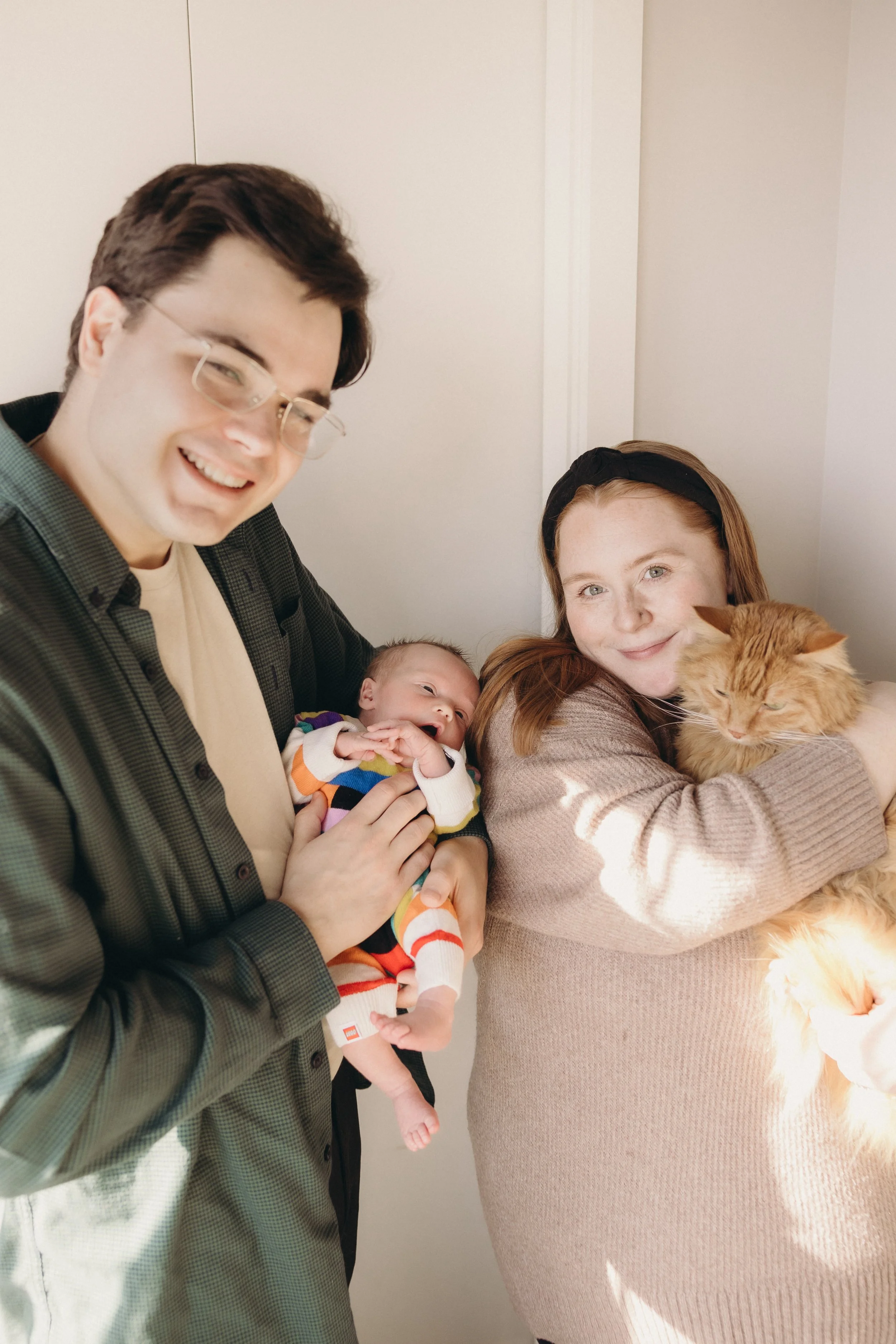 Family with cat and new baby smiling during family photo session