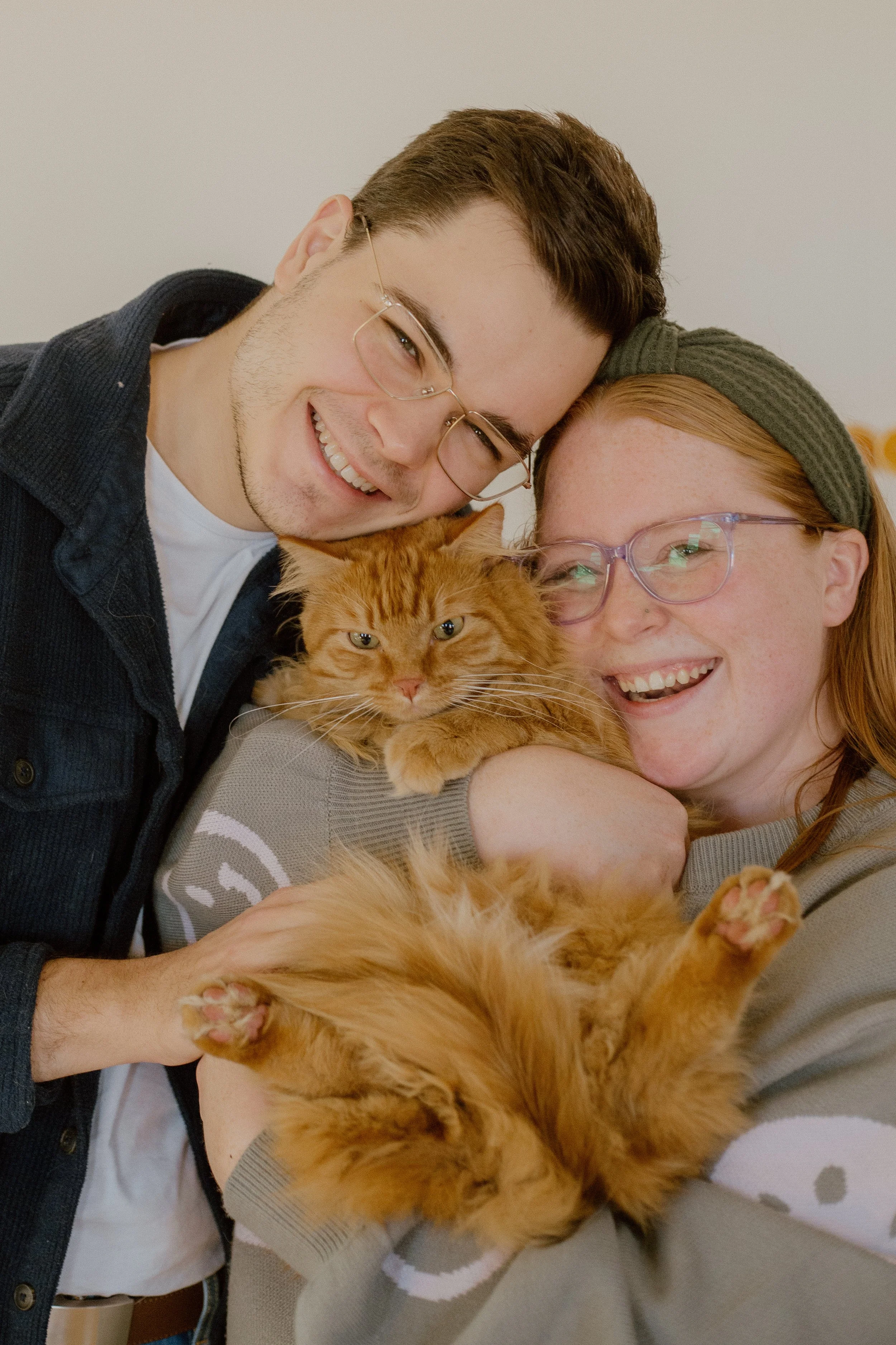Couple snuggled with their fluffy orange car during a family photo session
