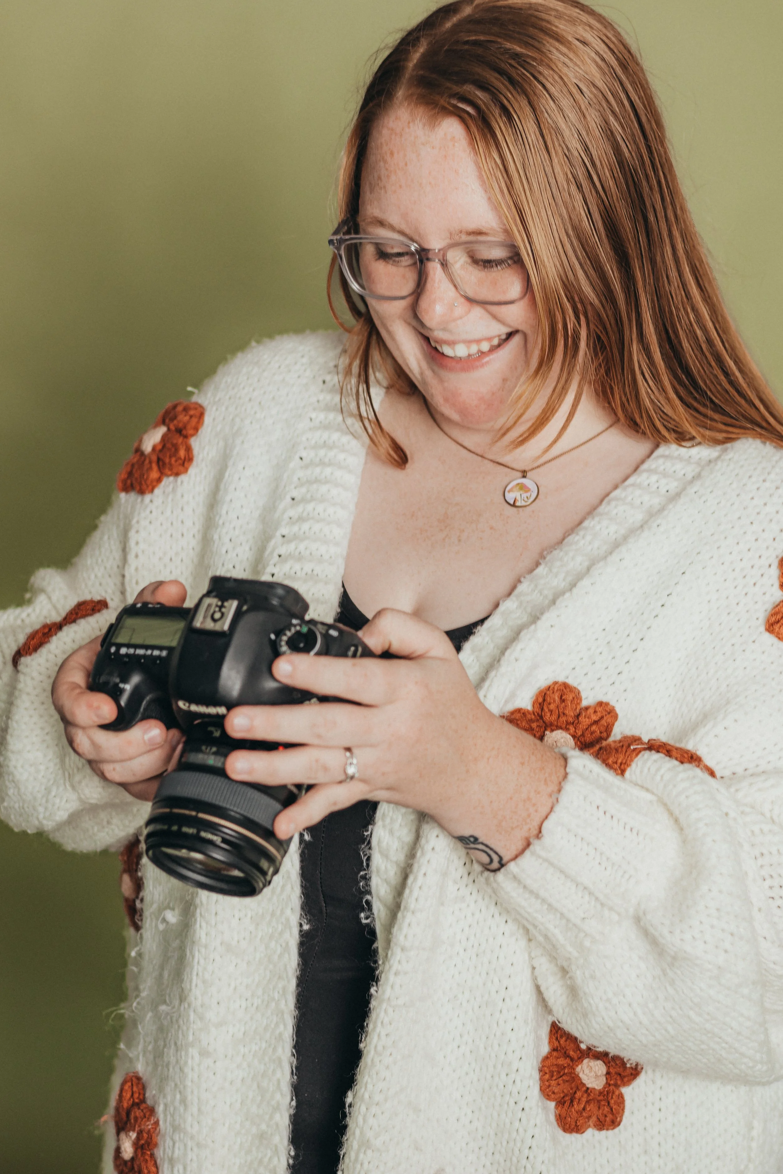 Woman photographer smiling down at camera during branding photoshoot