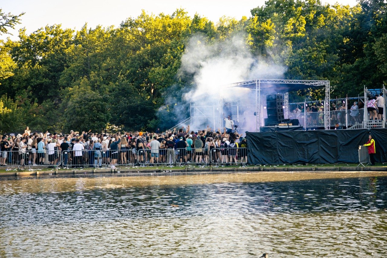 Outdoor concert by a lake with a large crowd and stage