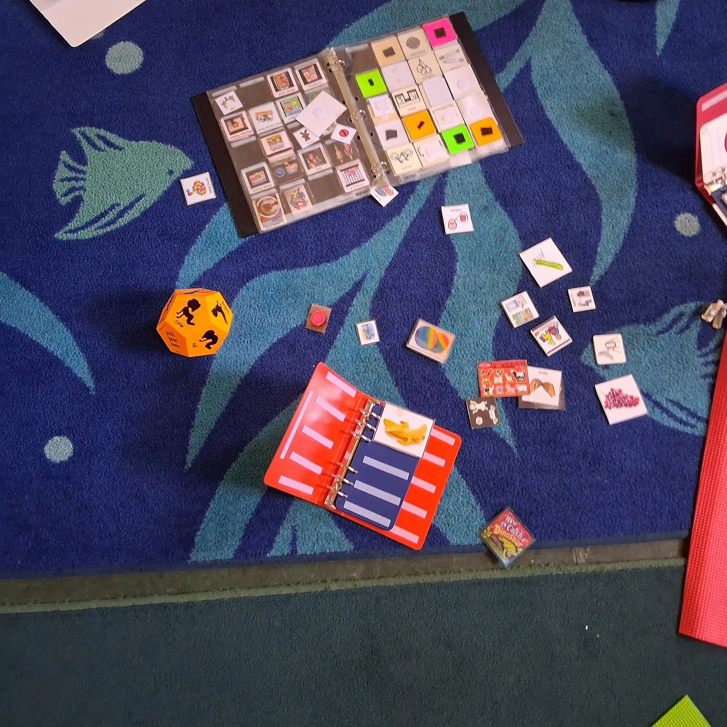 Colorful card game on a blue patterned carpet with various game pieces and cards scattered around.