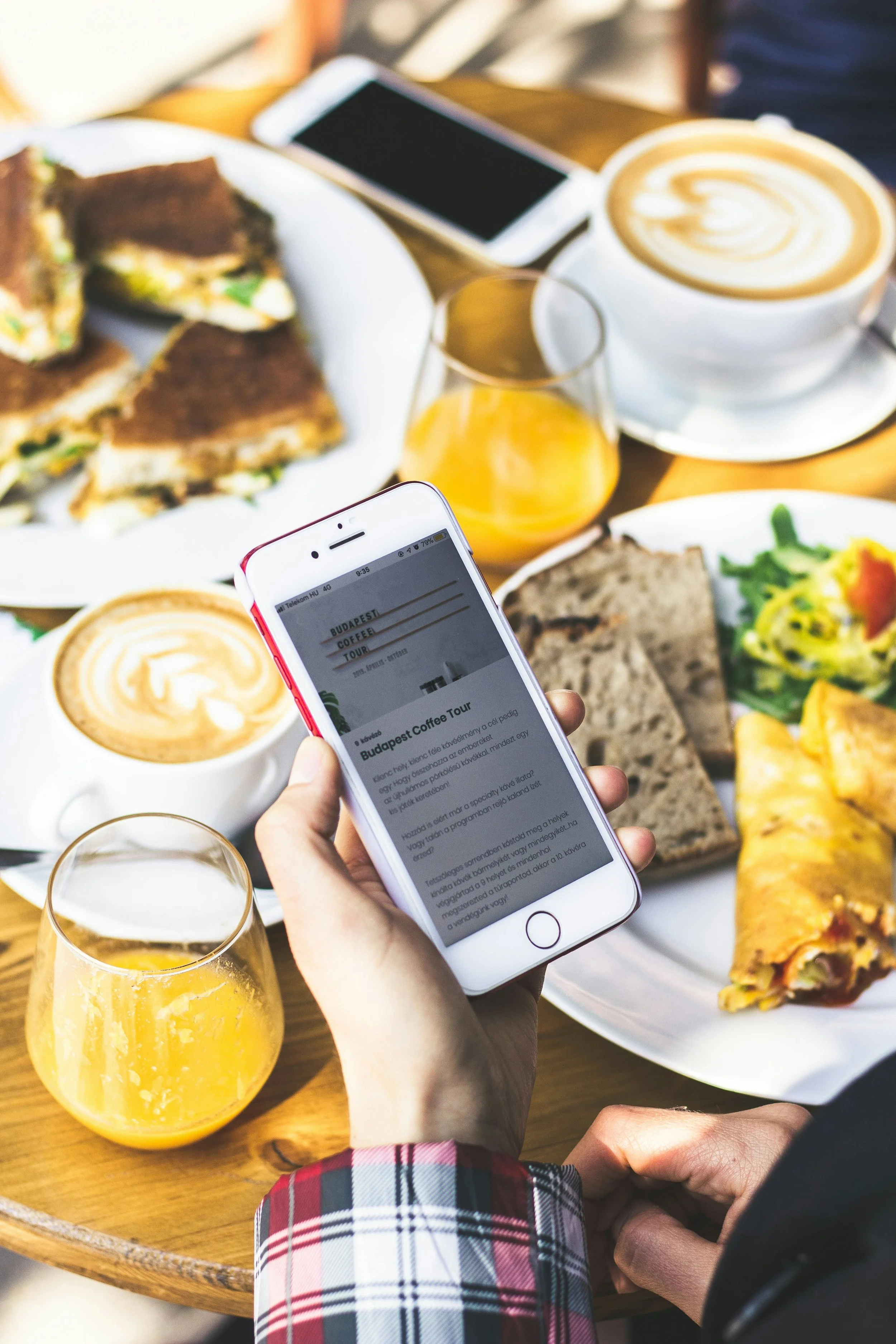 A person holding a smartphone over a table for a delivery app to order Aruba Eats food delivery service.