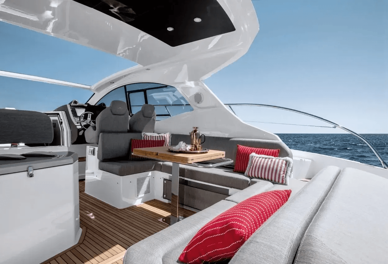 Luxury yacht interior with red striped cushions, a wooden table, and ocean view.