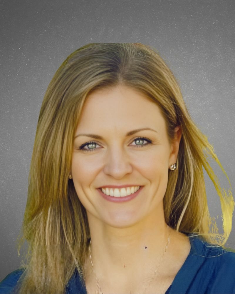 A woman with light brown hair and blue eyes smiling at the camera, wearing earrings and a necklace, against a gray background with a starry pattern.