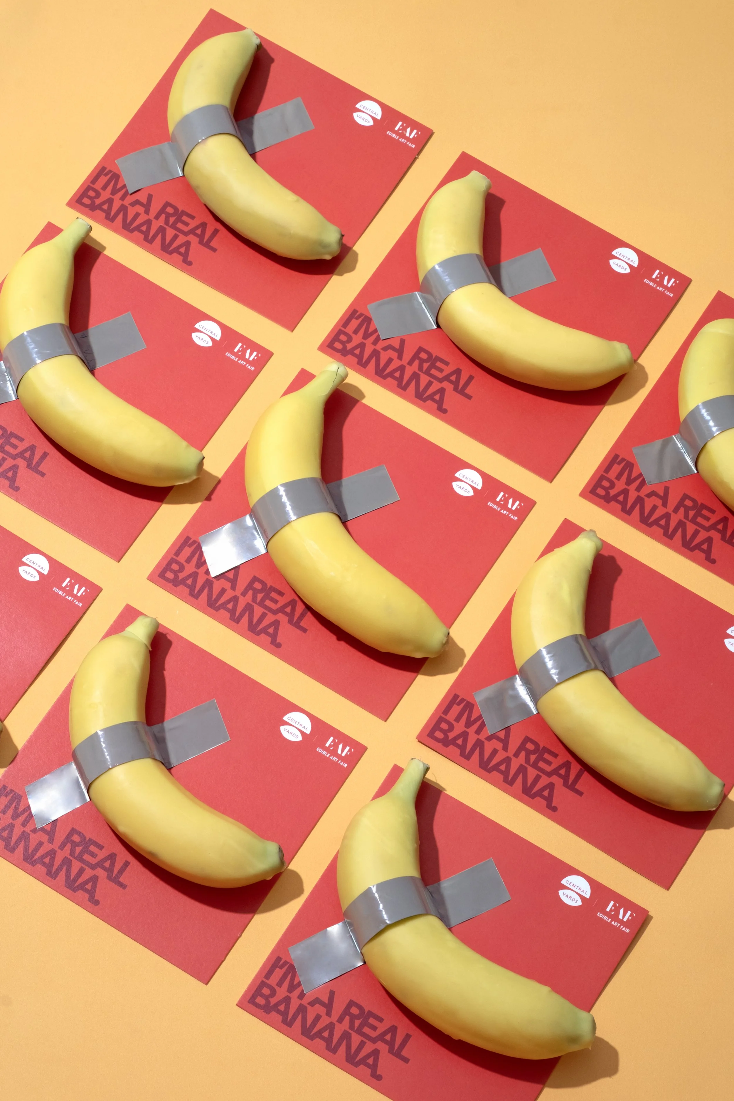 Six bananas on red cards with the text "I'm a real banana" arranged on an orange surface.