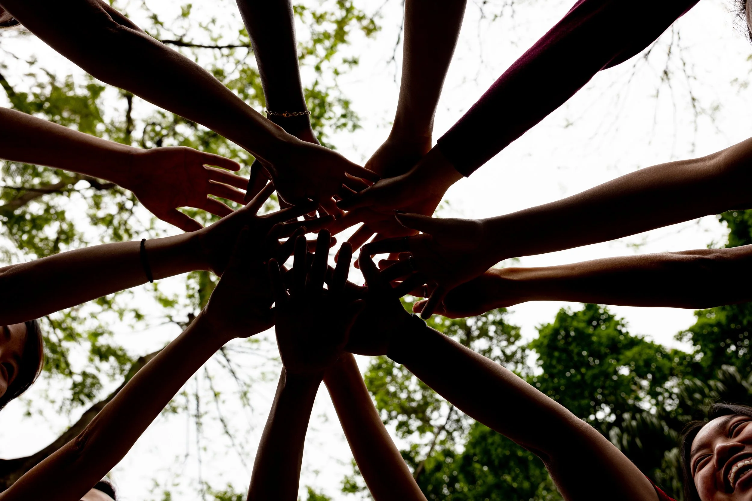 Many hands touching at the center