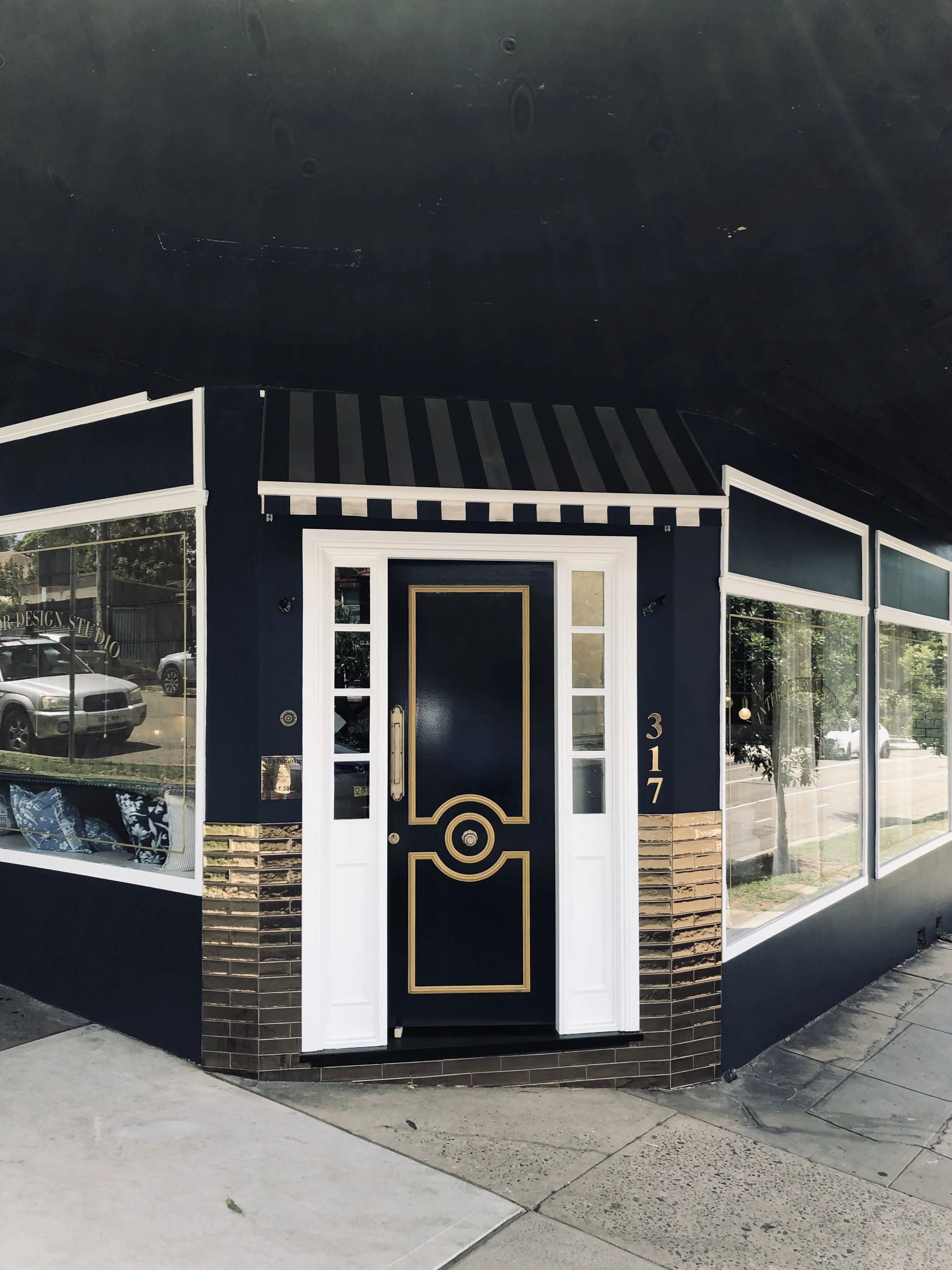Exterior of a building with a black and gold door, brick accents, and large windows, located at 317.