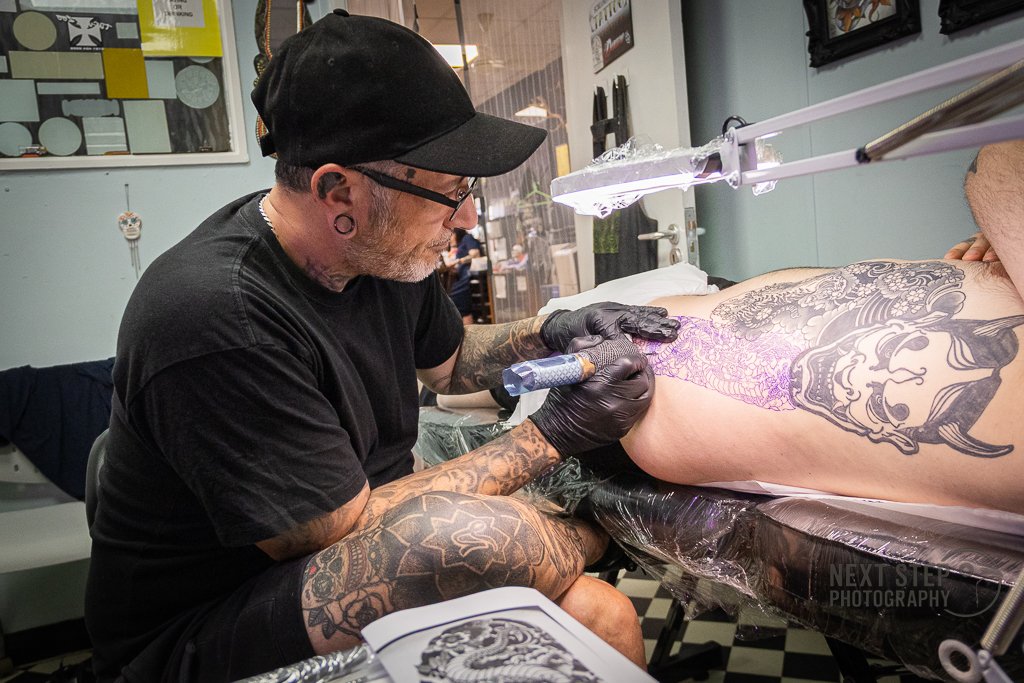 A man tattooing someone in a studio
