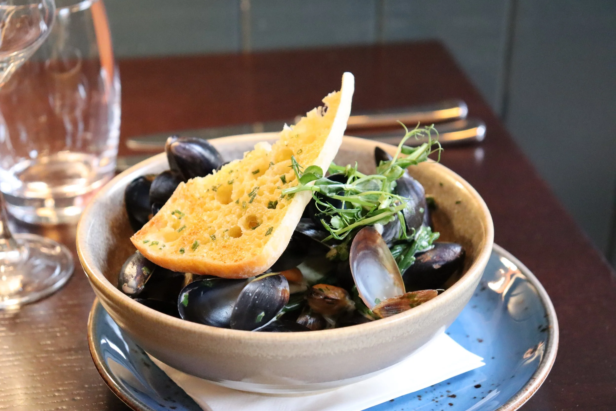 a bowl of served mussels with bread