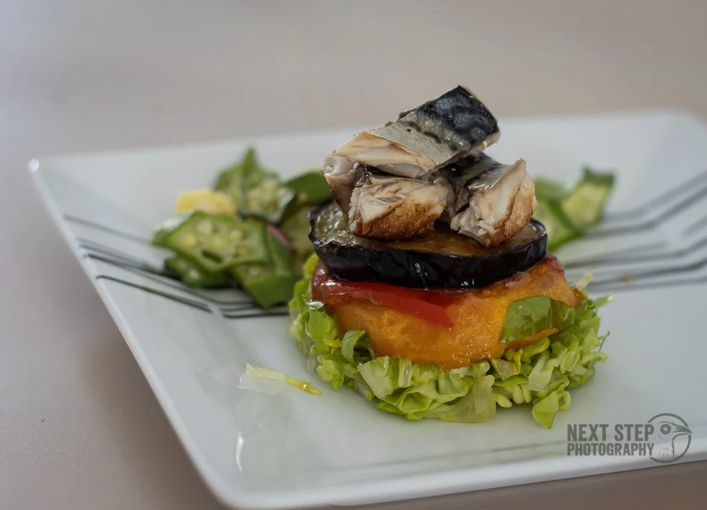 A plated canapé with fish and eggplant on a bed of lettuce