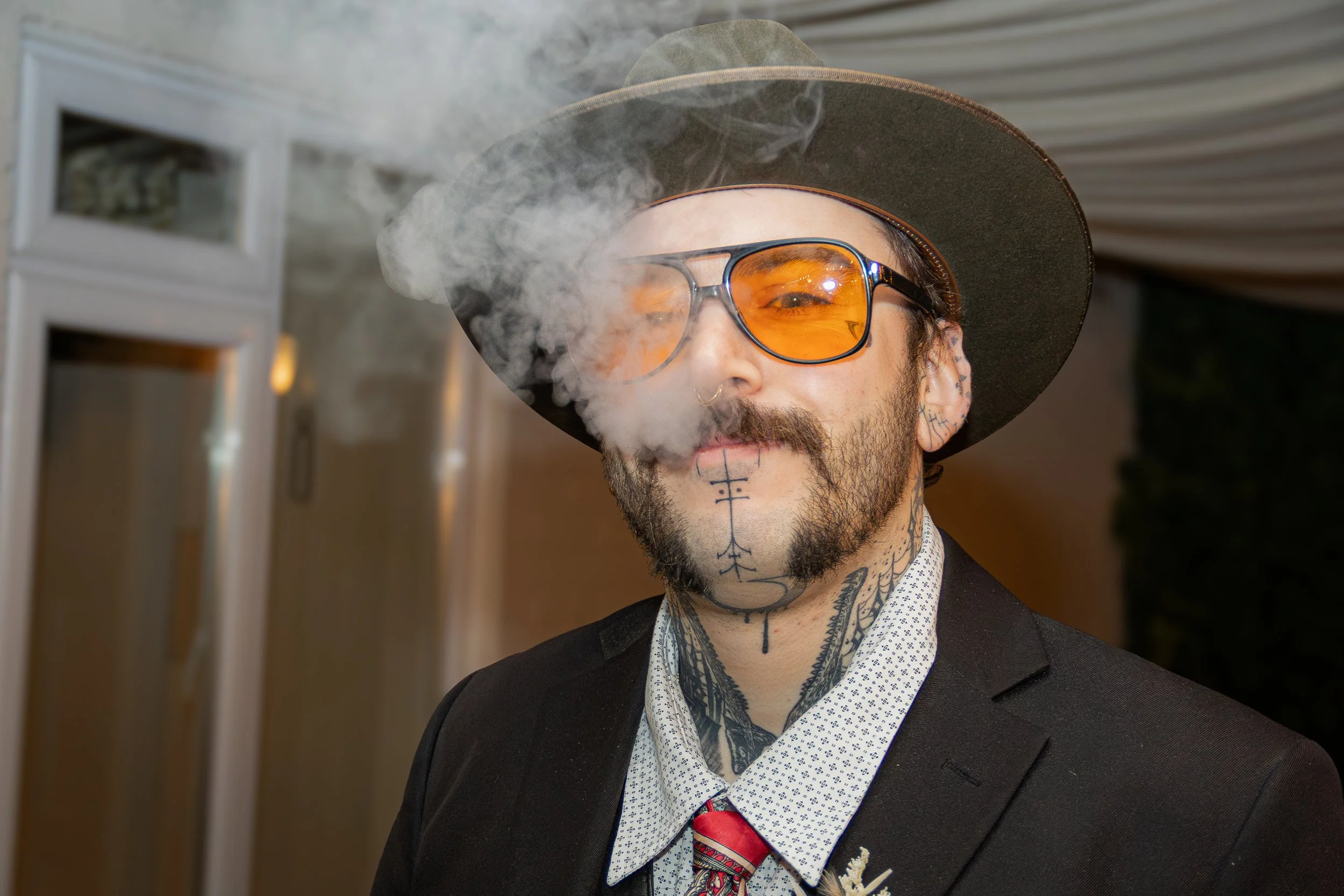 A stylish man in a hat and glasses smoking