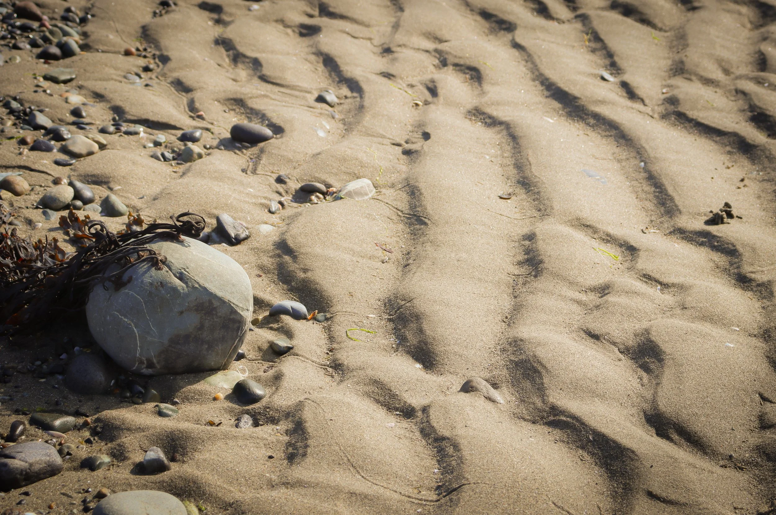 A stone and pebbles on a sandy beach