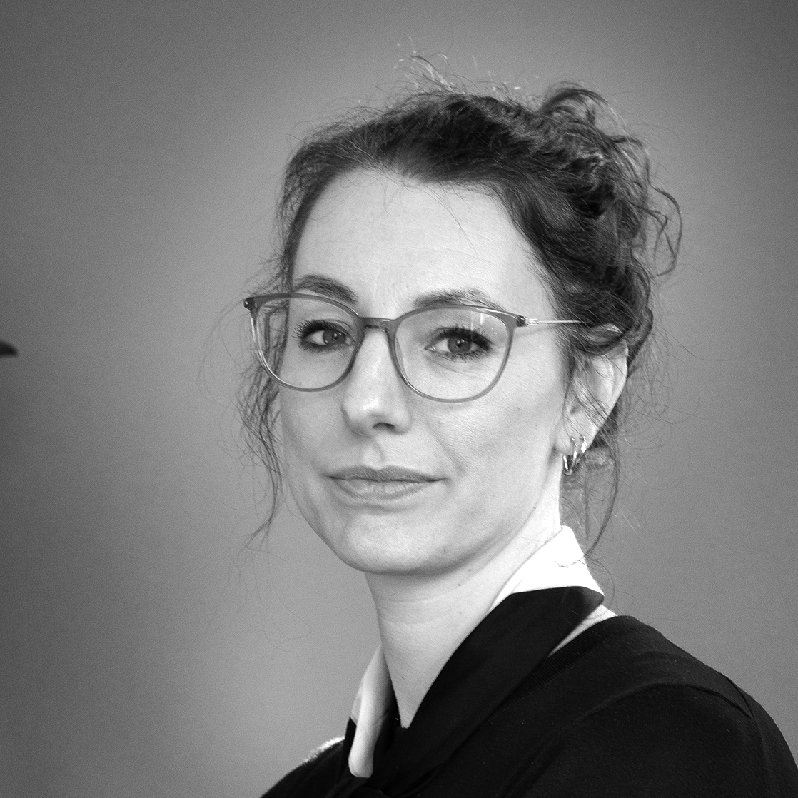 Black and white portrait of a woman wearing glasses and looking at the camera.