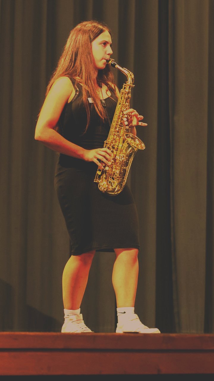 Eine junge Frau spielt auf einer Bühne Saxophon.