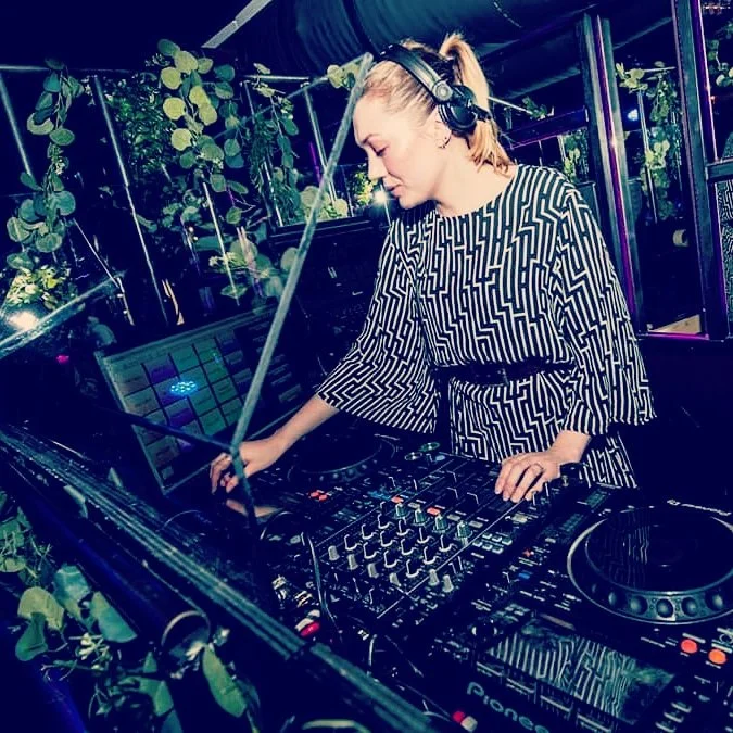 DJ som spiller musikk på en miksestasjon i et dekorert rom med planter.