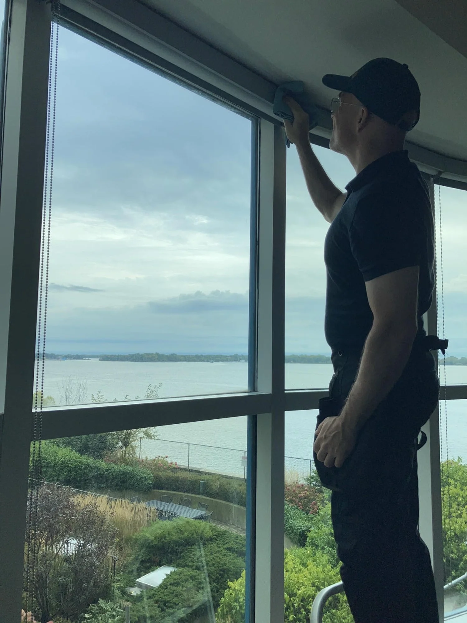 Trevor cleaning a window overlooking a garden and lake.