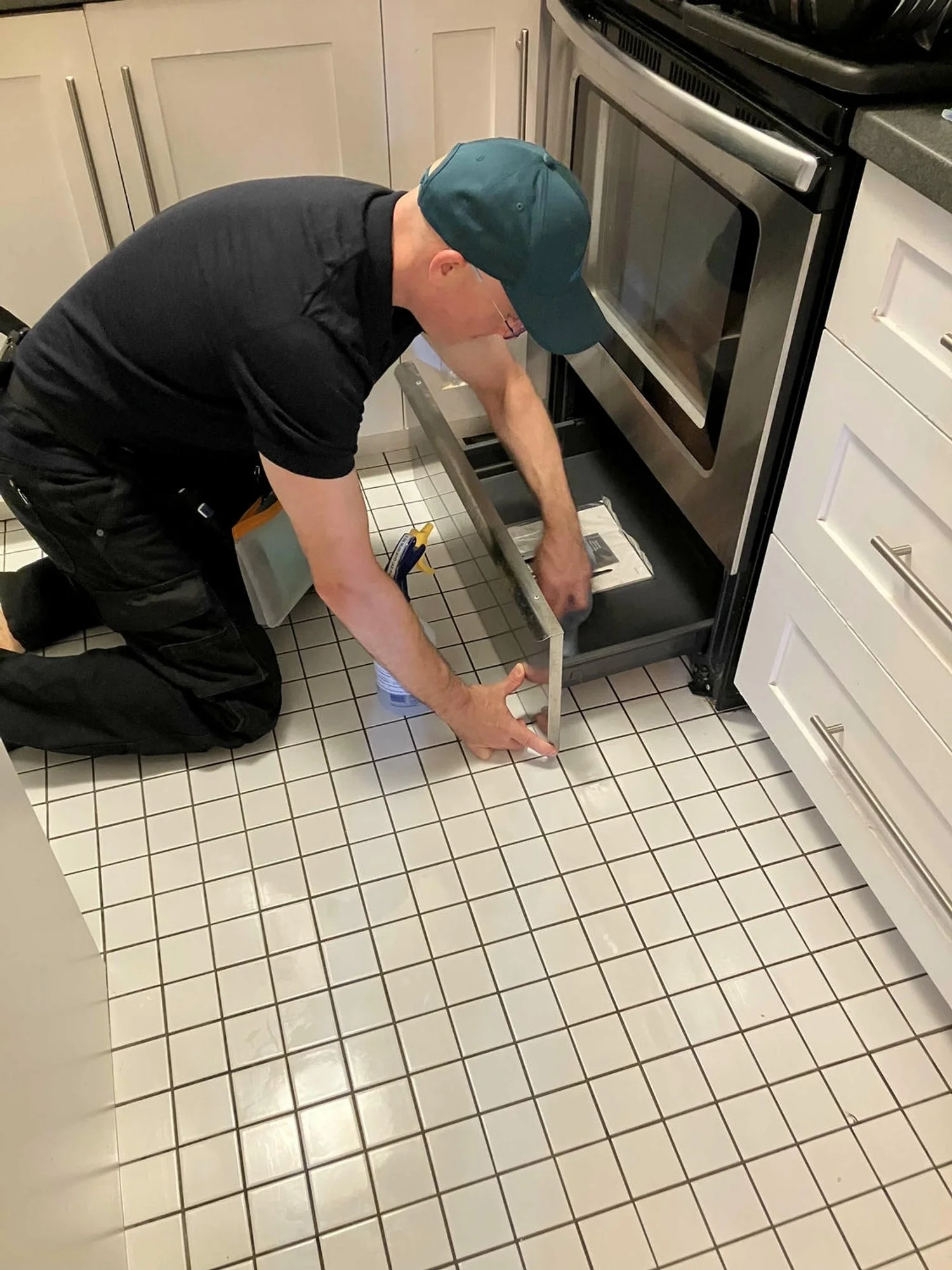 Trevor, in a white tiled kitchen cleaning an oven drawer.